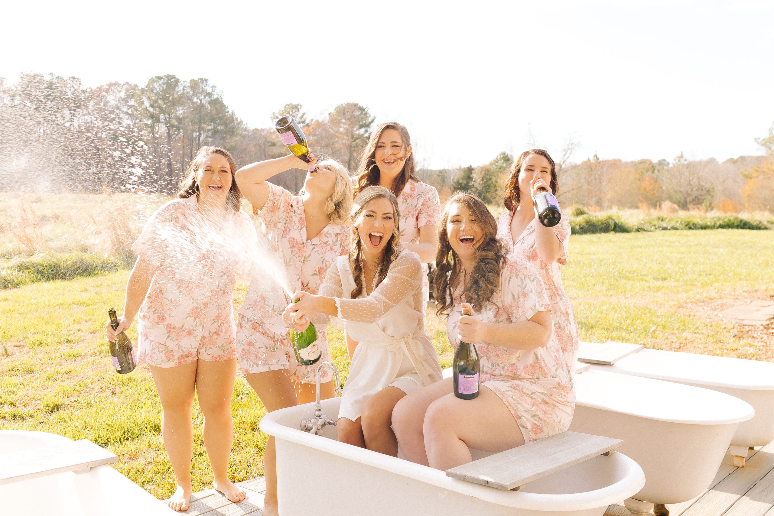 bride pops champagne with her best friends on her wedding day the Meadows Raleigh in North Carolina