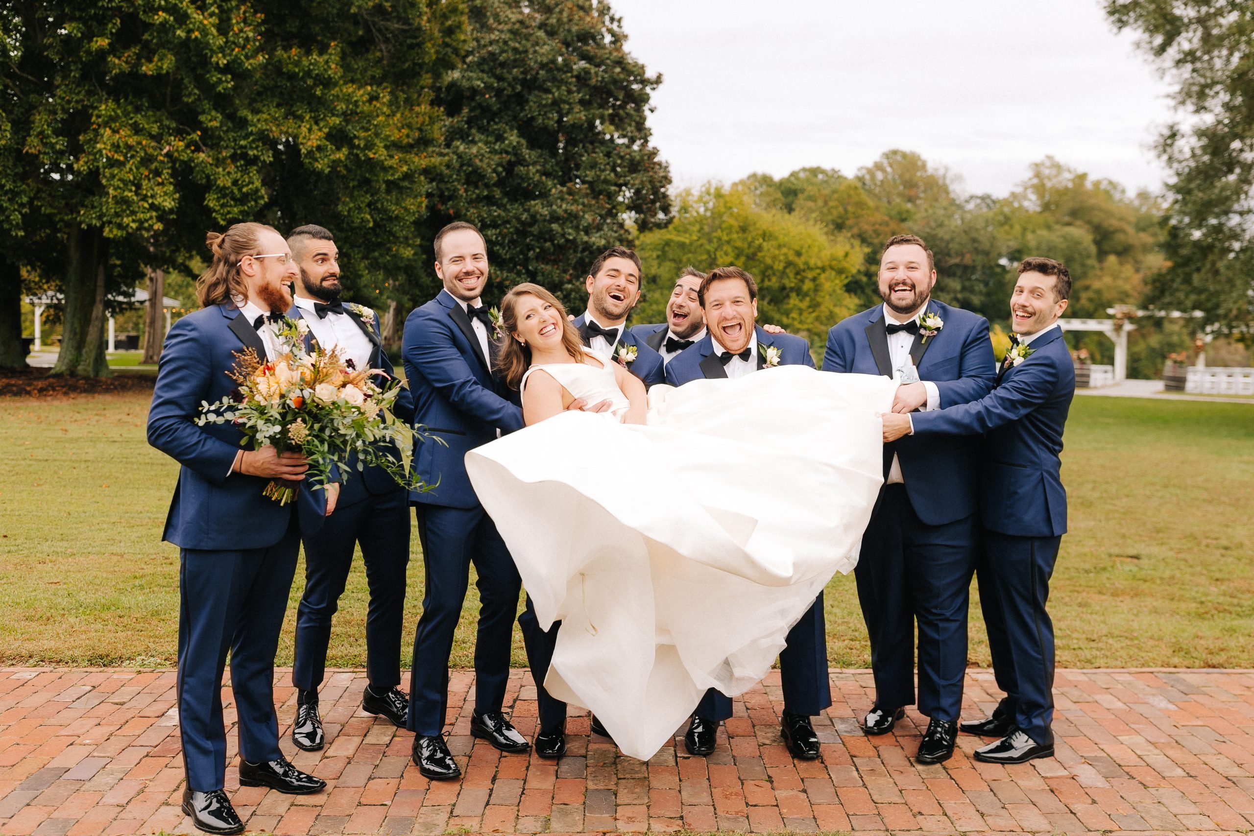 bride is held by groomsmen for wedding day fun at Hollyfield Manor in Richmond, VA