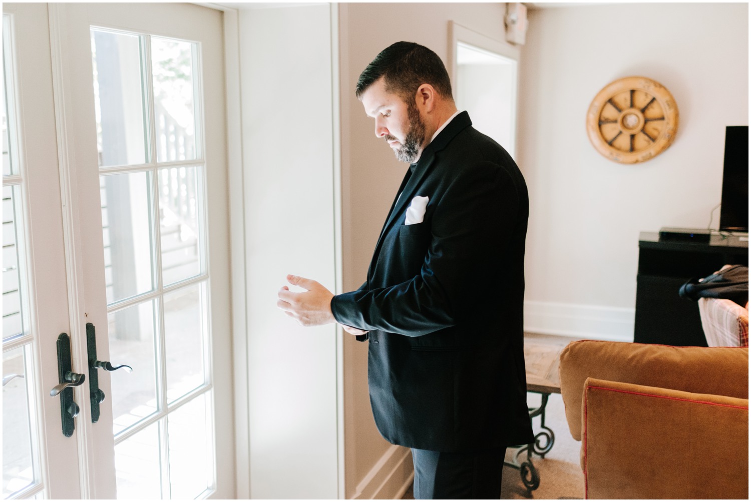 groom adjusts suit jacket before wedding day in Highlands NC