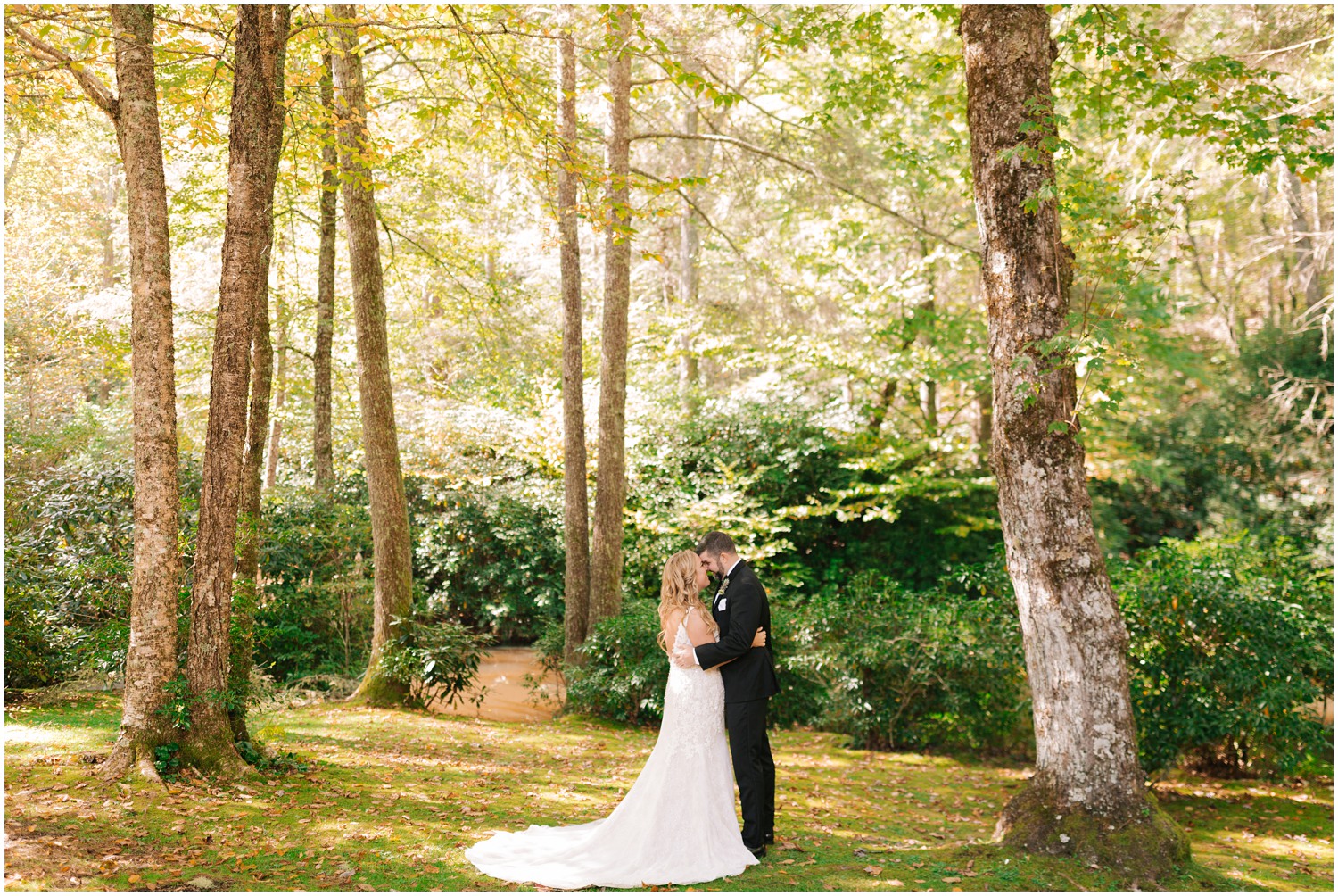 bride and groom stand nose to nose hugging each other in woods at Old Edwards Inn