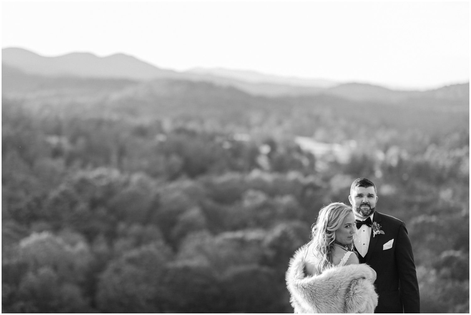 dramatic wedding portrait of bride with fur wrap and groom on mountaintop 