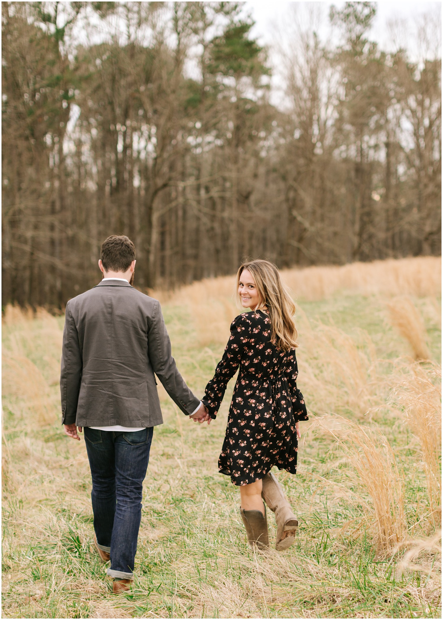 couple walks in field while bride looks over shoulder at The Meadows Raleigh