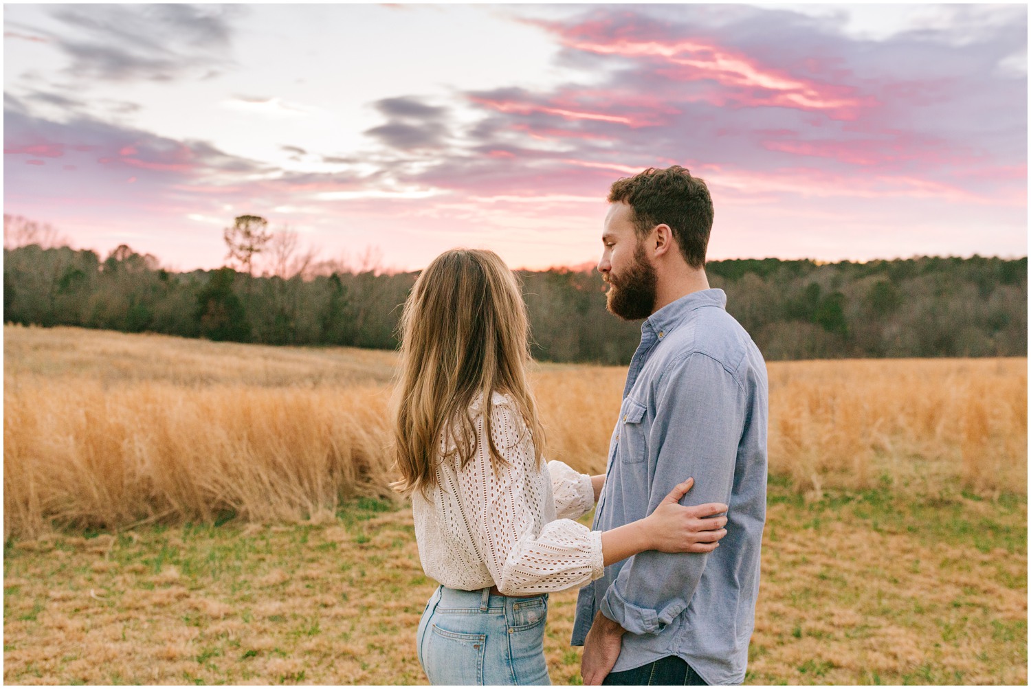 engaged couple looks at purple sunset at The Meadows Raleigh