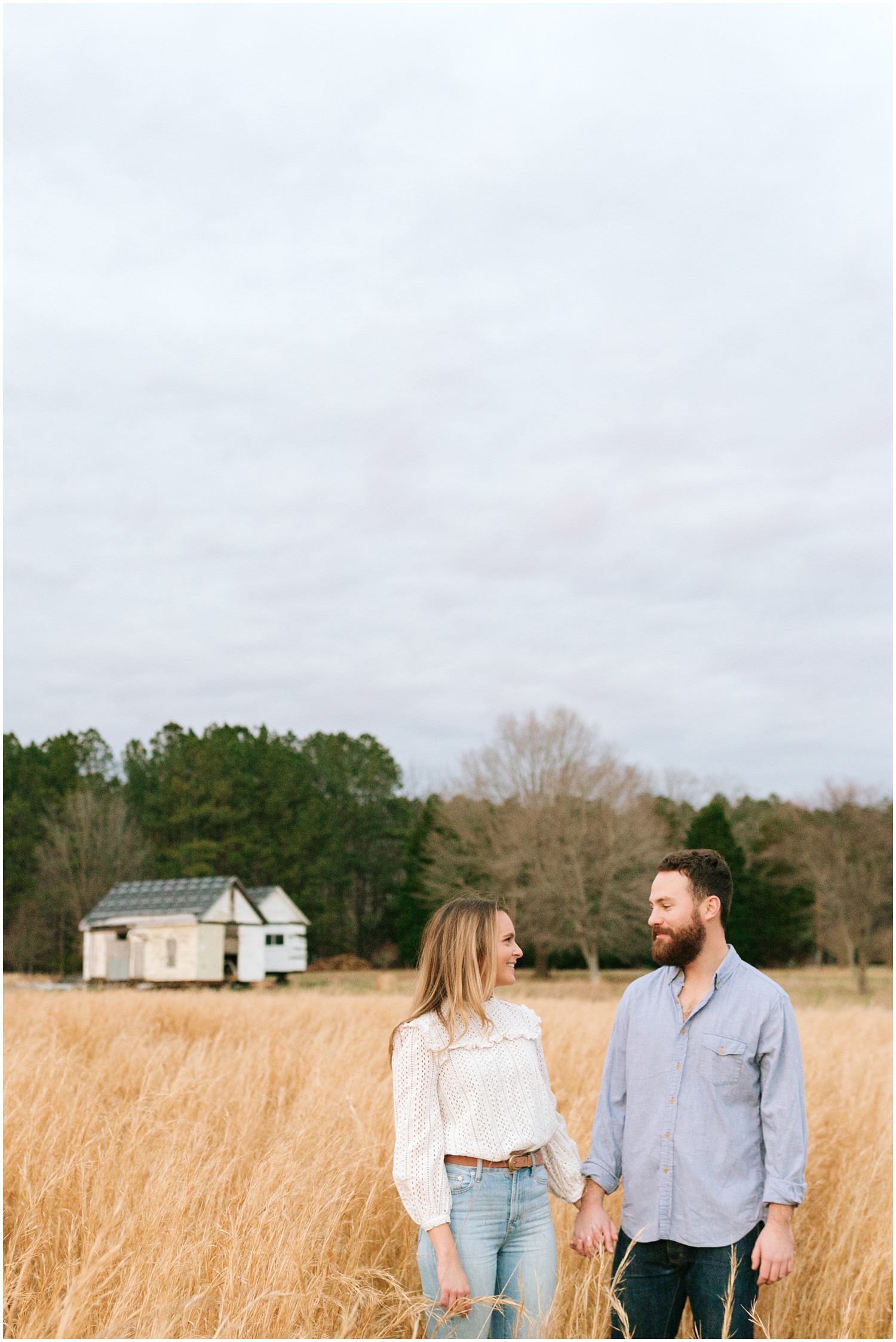 couple holds hands during fall engagement session at The Meadows Raleigh