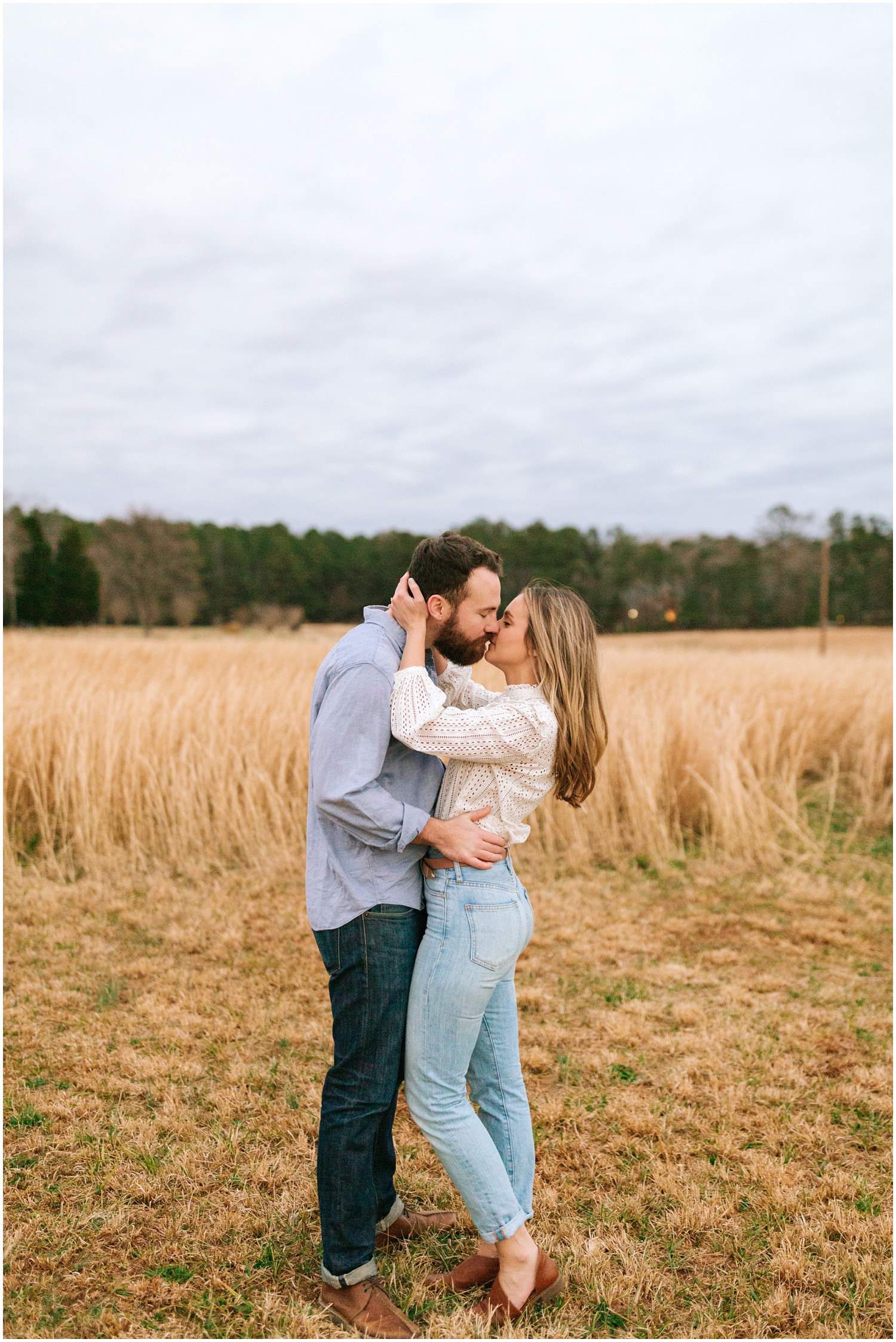 engaged couple kisses in field during engagement photos at The Meadows Raleigh