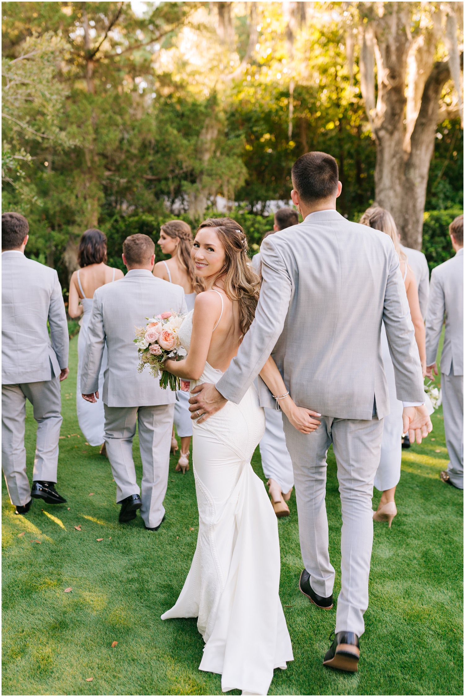 newlyweds walk through Wrightsville Manor gardens with bridal party 