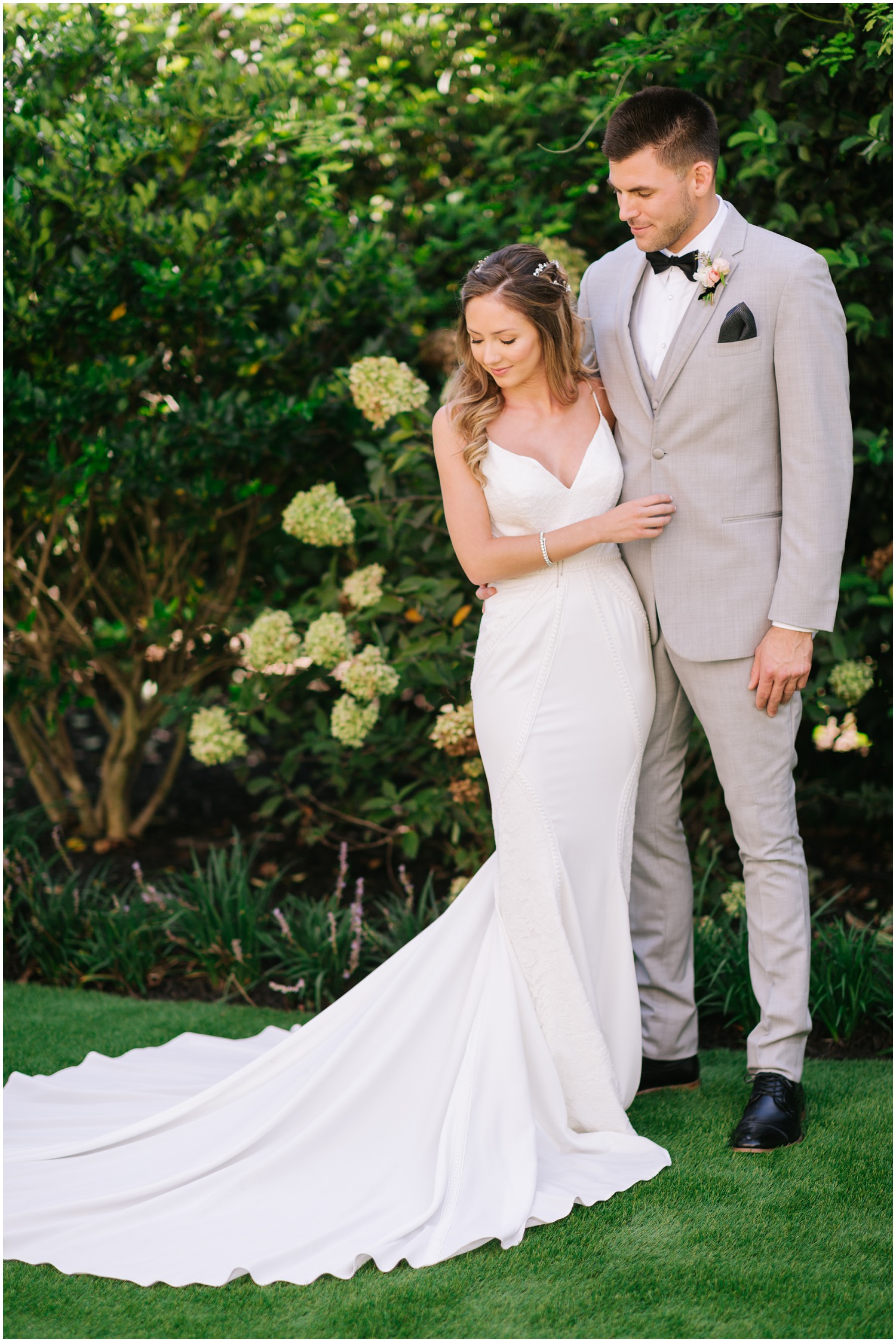 bride and groom look at bride's train