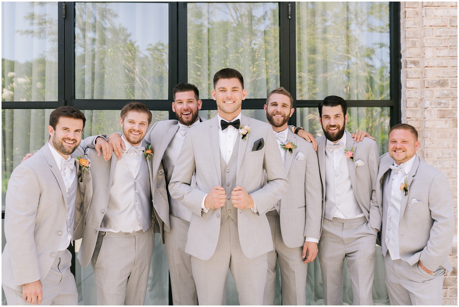 groom poses with six groomsmen in grey suits