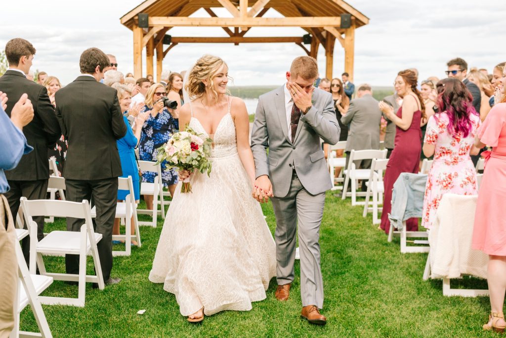 Winston Salem Wedding Photographer captures the bride and groom walking down the aisle after being announced as husband and wife. The groom is crying joyful tears and the bride is full of happy smiles.