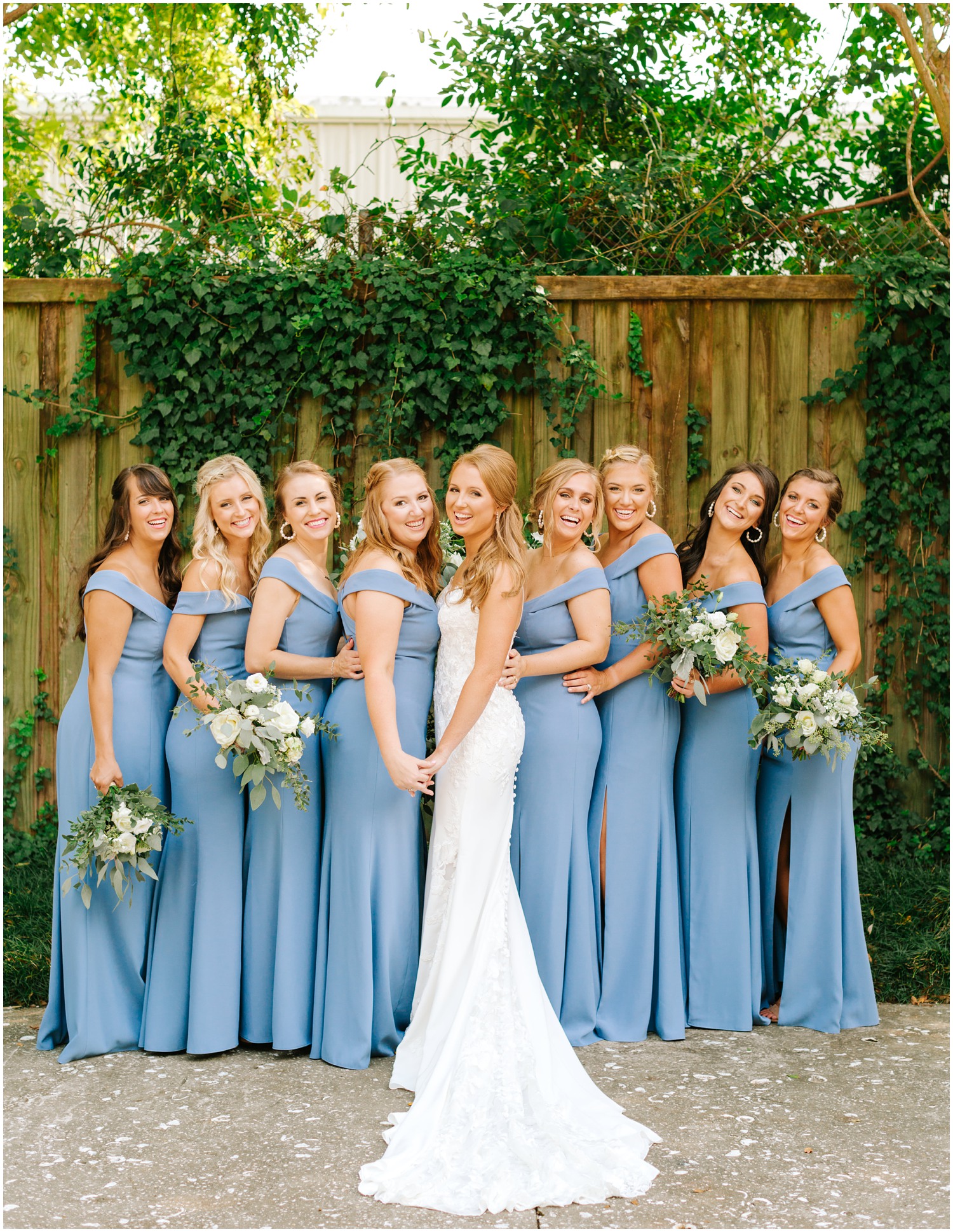 bride poses with bridesmaids in blue gowns in Wilmington NC