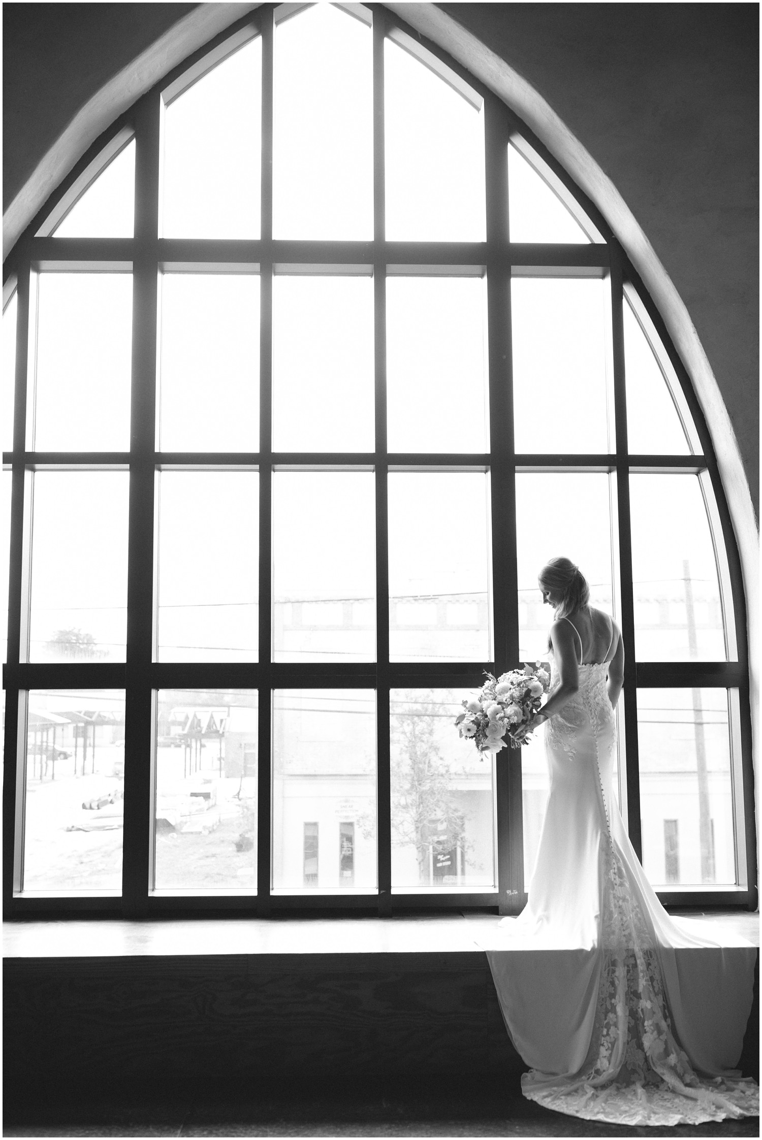 black and white bridal portrait at Brooklyn Arts Center of bride with train hanging off windowsill 