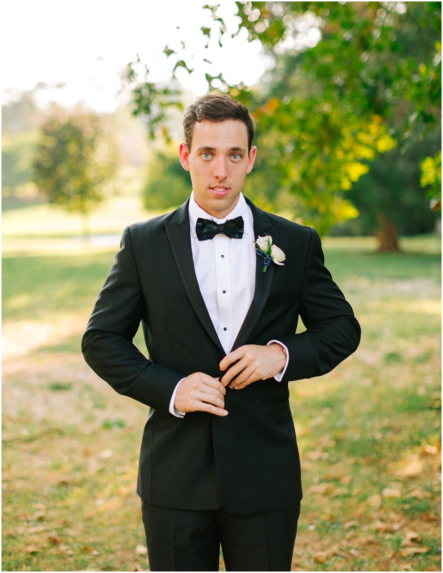 groom looks at Chelsea Renay Photography while re-buttoning tux jacket