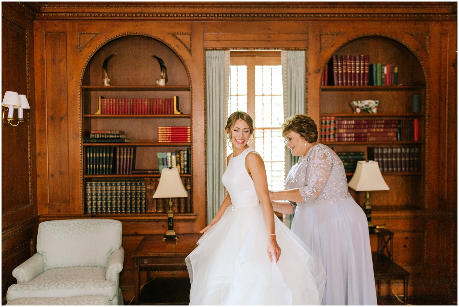 mother helps bride with wedding dress in library at Graylyn Estate
