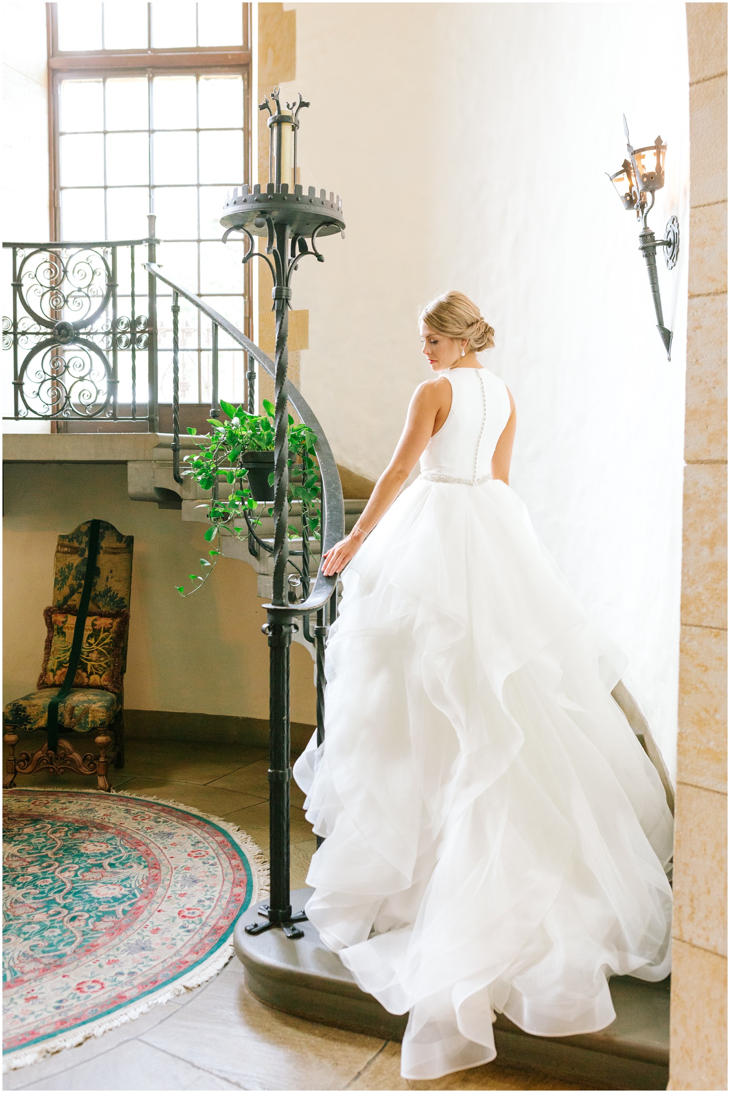 bride stands with wedding gown trailing behind her on staircase at Graylyn Estate
