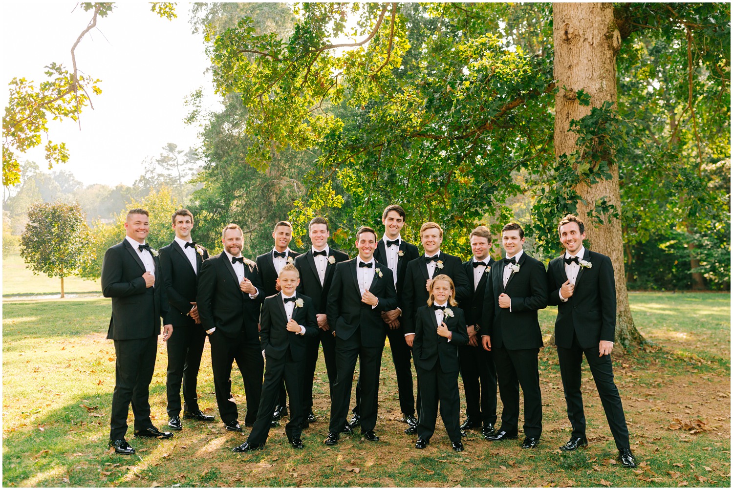 groom and groomsmen in black tuxes smile at Chelsea Renay Photography