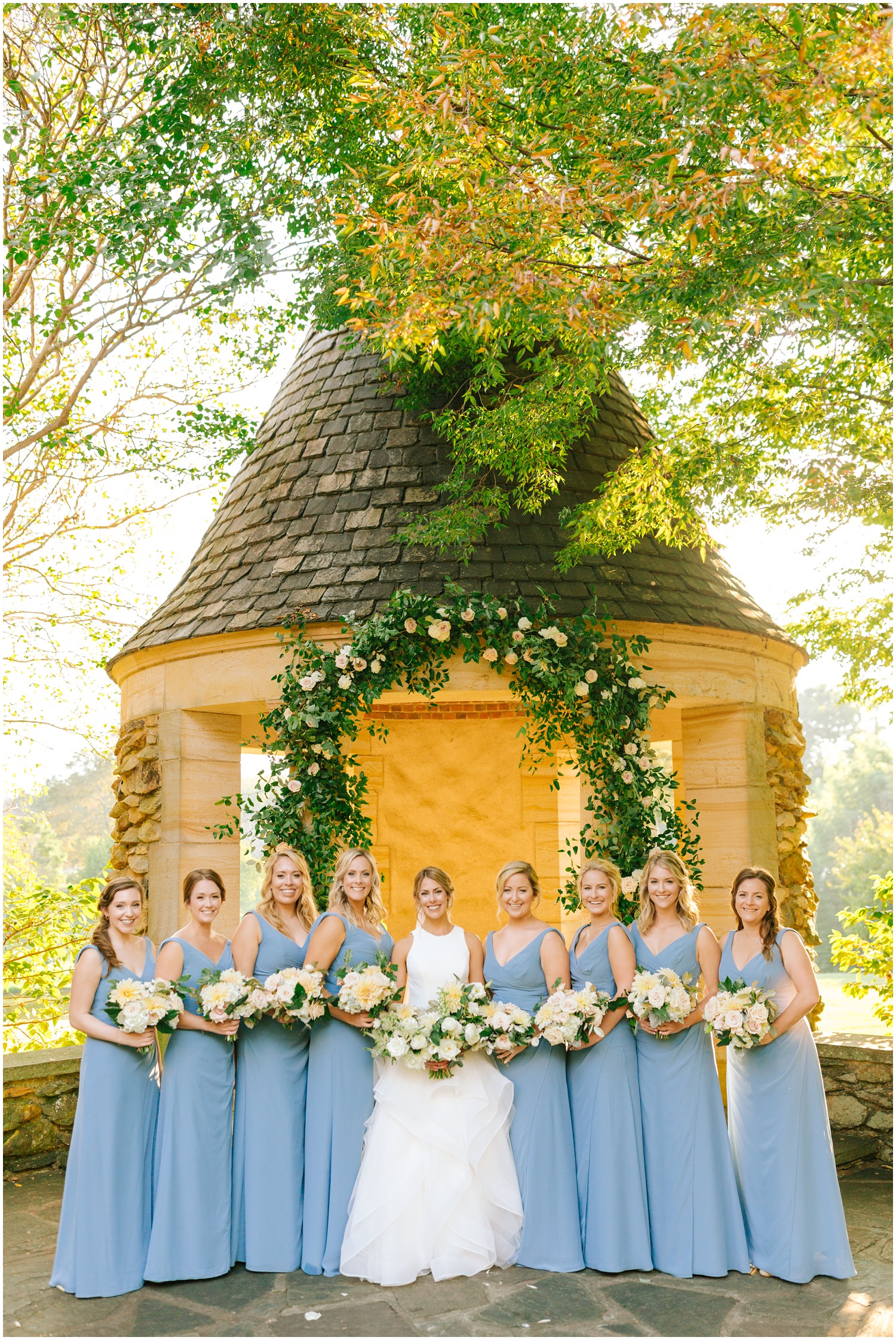 bridesmaids in light blue gowns hold bouquets with bride at Graylyn Estate
