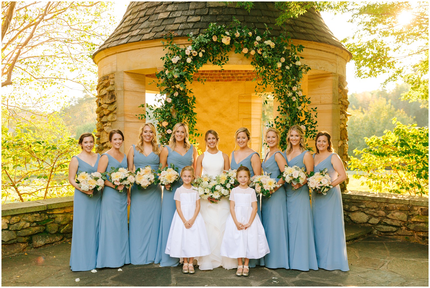 bride with 8 bridesmaids in blue gowns and 2 flower girls in white dresses at Graylyn Estate