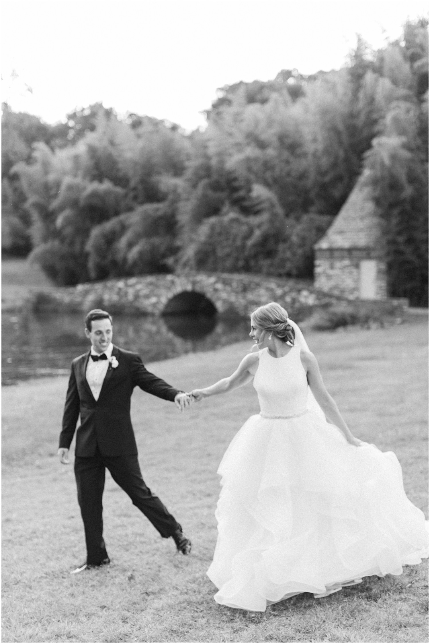 black and white wedding portrait of bride and groom walking at Graylyn Estate
