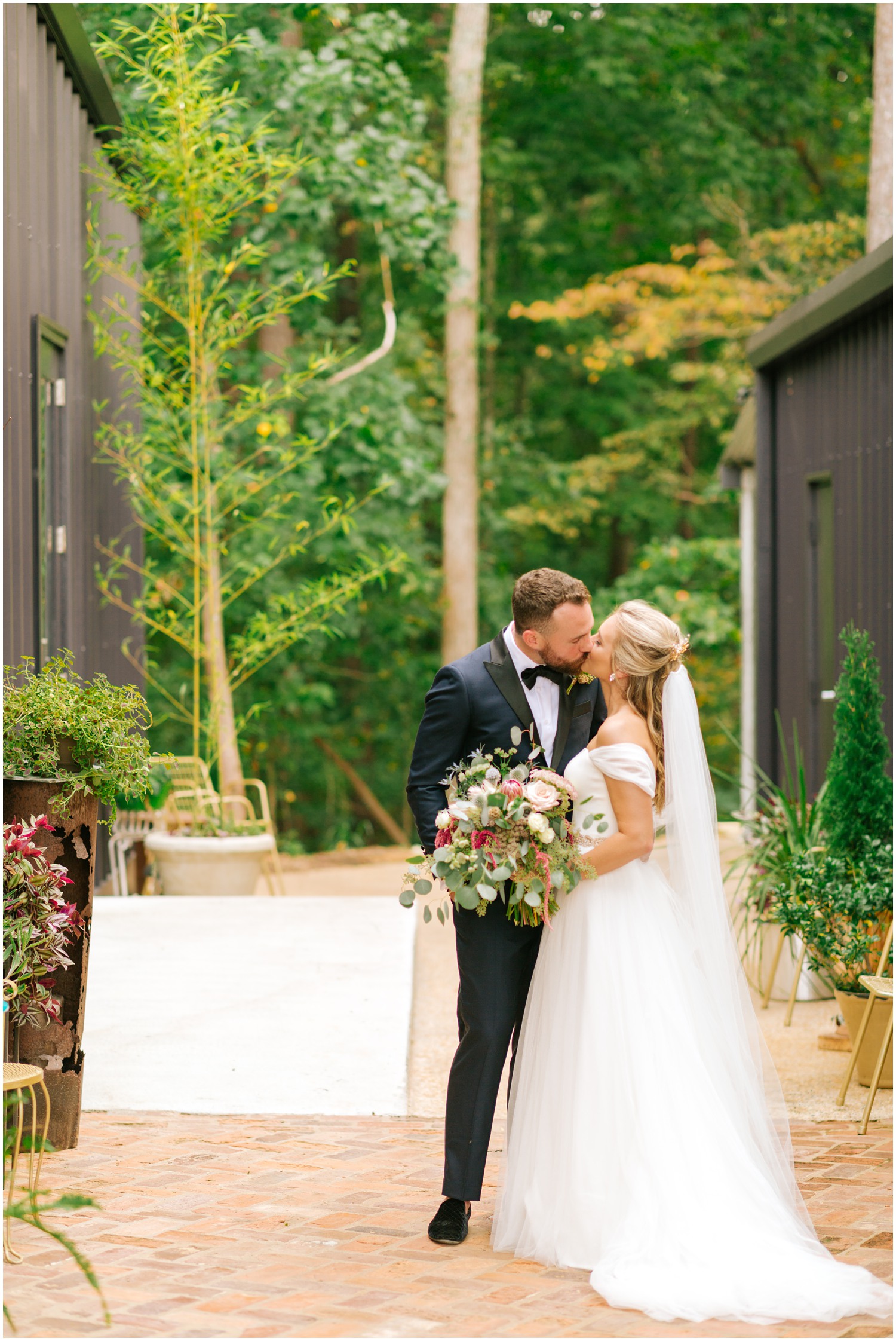 bride and groom kiss outside The Meadows Raleigh