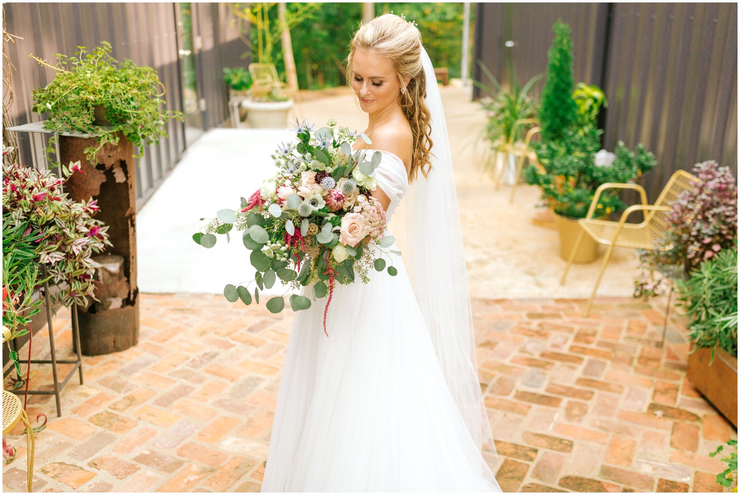 bride looks at bouquet during bridal portraits at The Meadows Raleigh