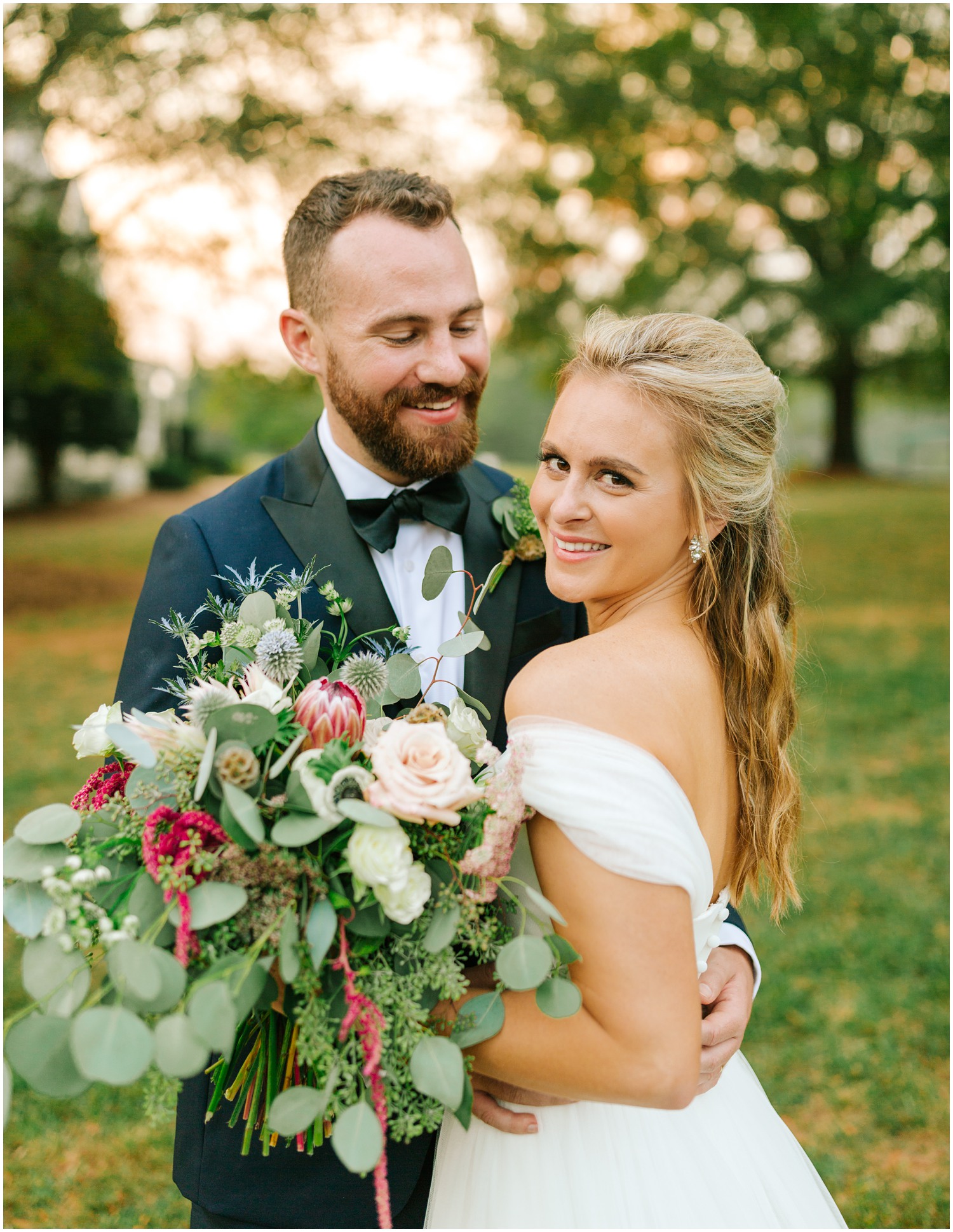 bride and groom smile during portraits at sunset