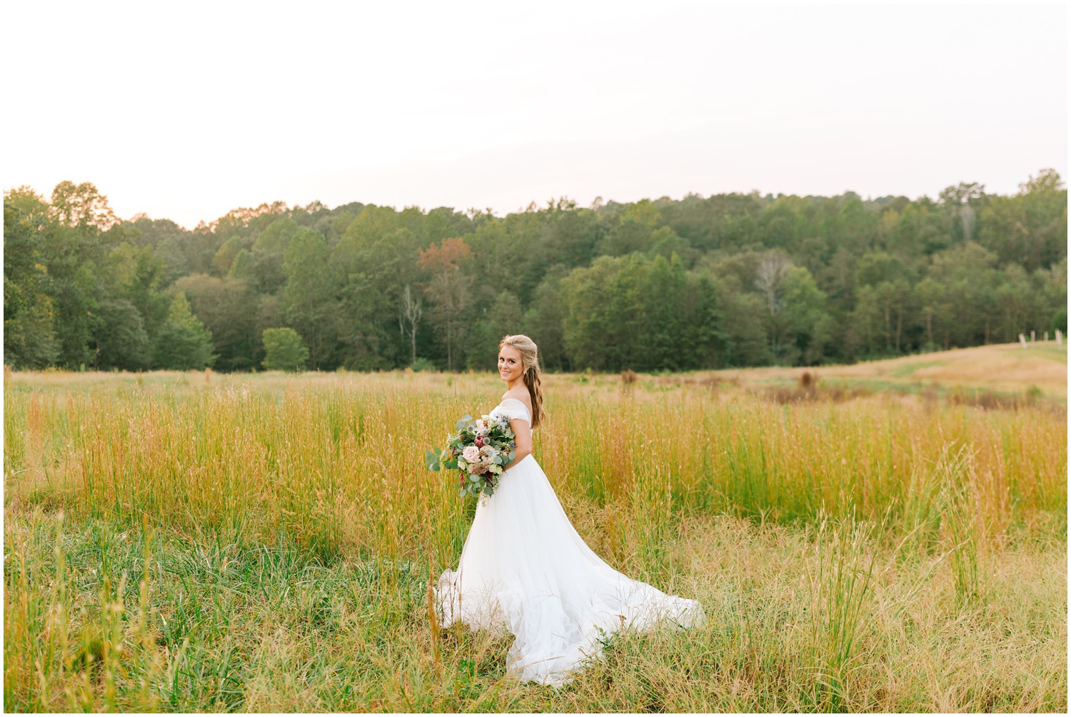 bridal portrait with bouquet and dress trailing in field at The Meadows Raleigh