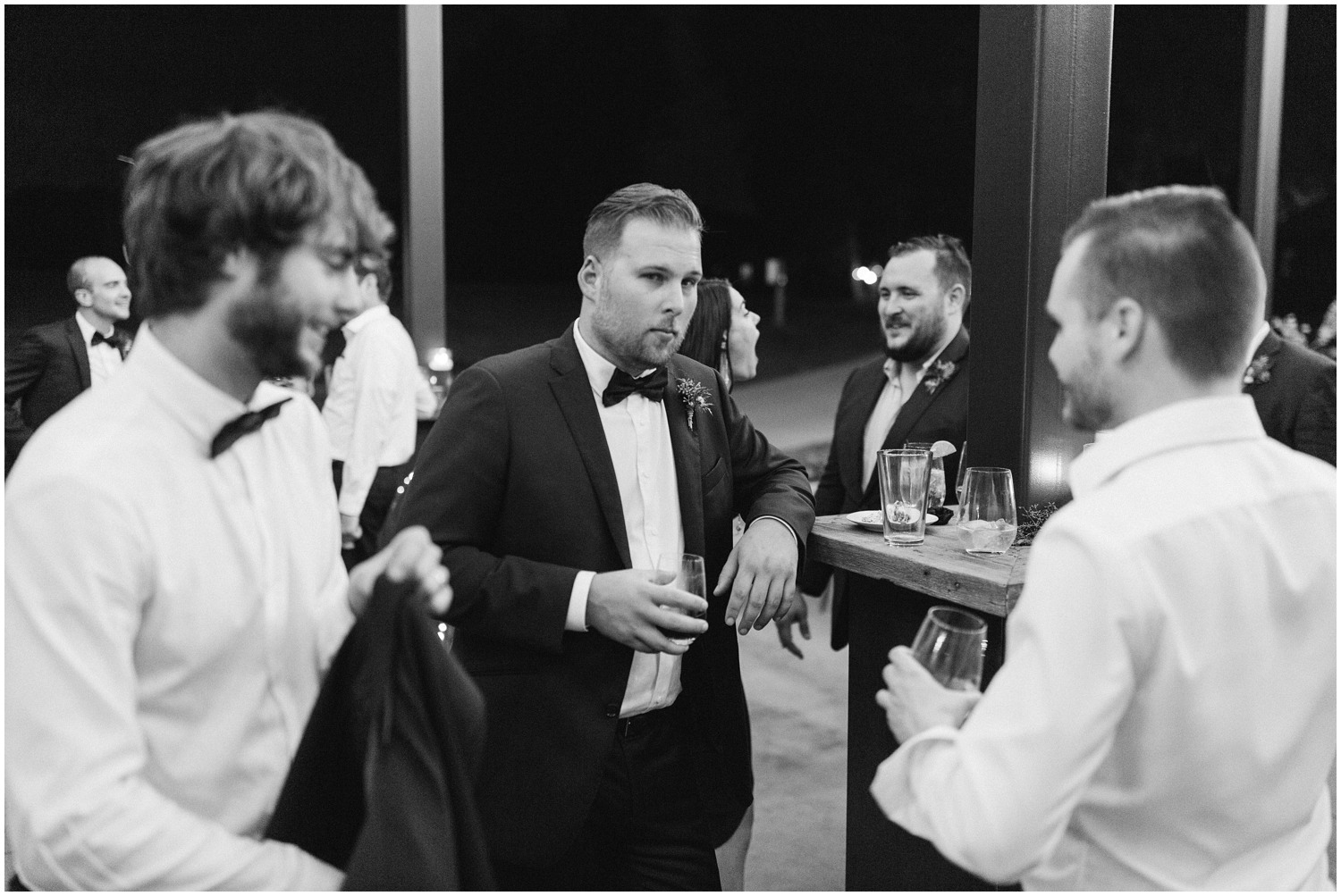 groomsmen chat by bar at Wedding at The Meadows Raleigh wedding reception