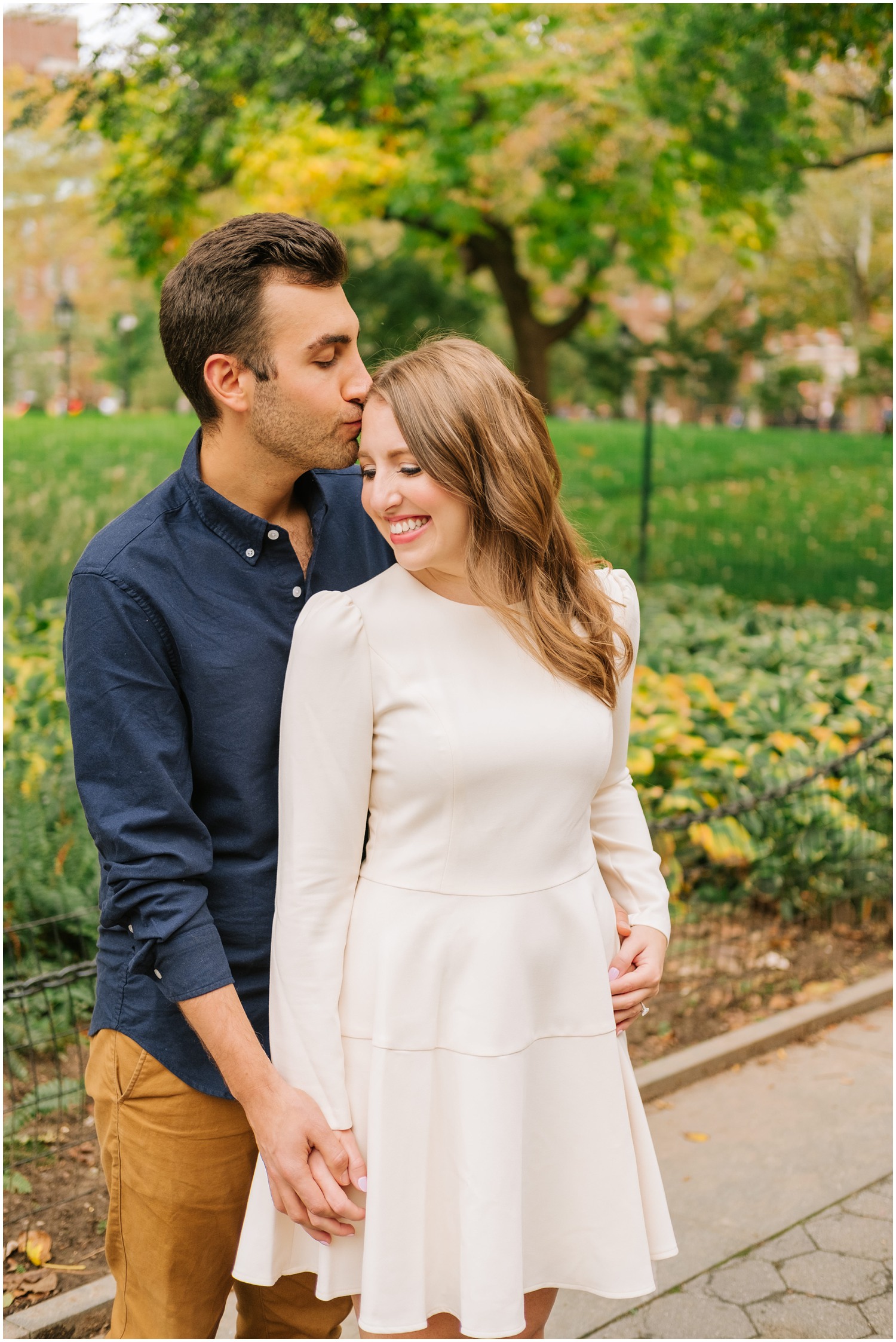 groom kisses bride in ecru dress during NYC engagement photos