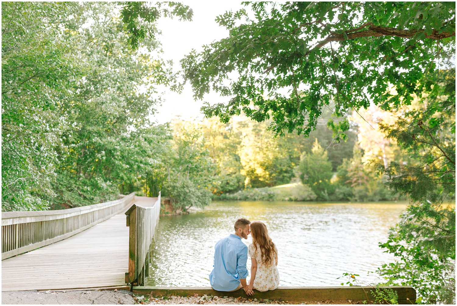 engaged couple sits along lake photographed by Chelsea Renay