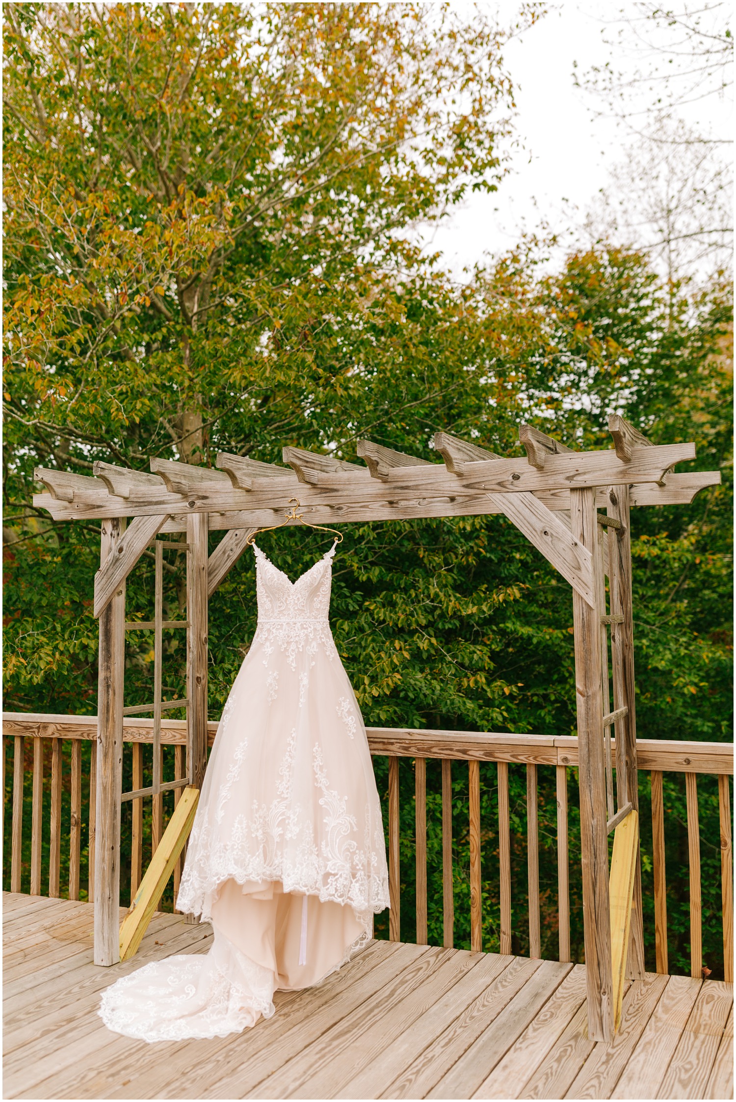 wedding dress with blush undertones hangs on arbor at  Medaloni Cellars