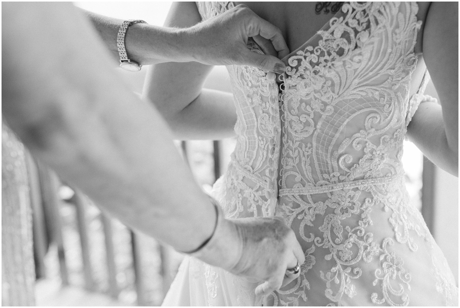 mother of the bride adjusts wedding dress for bride