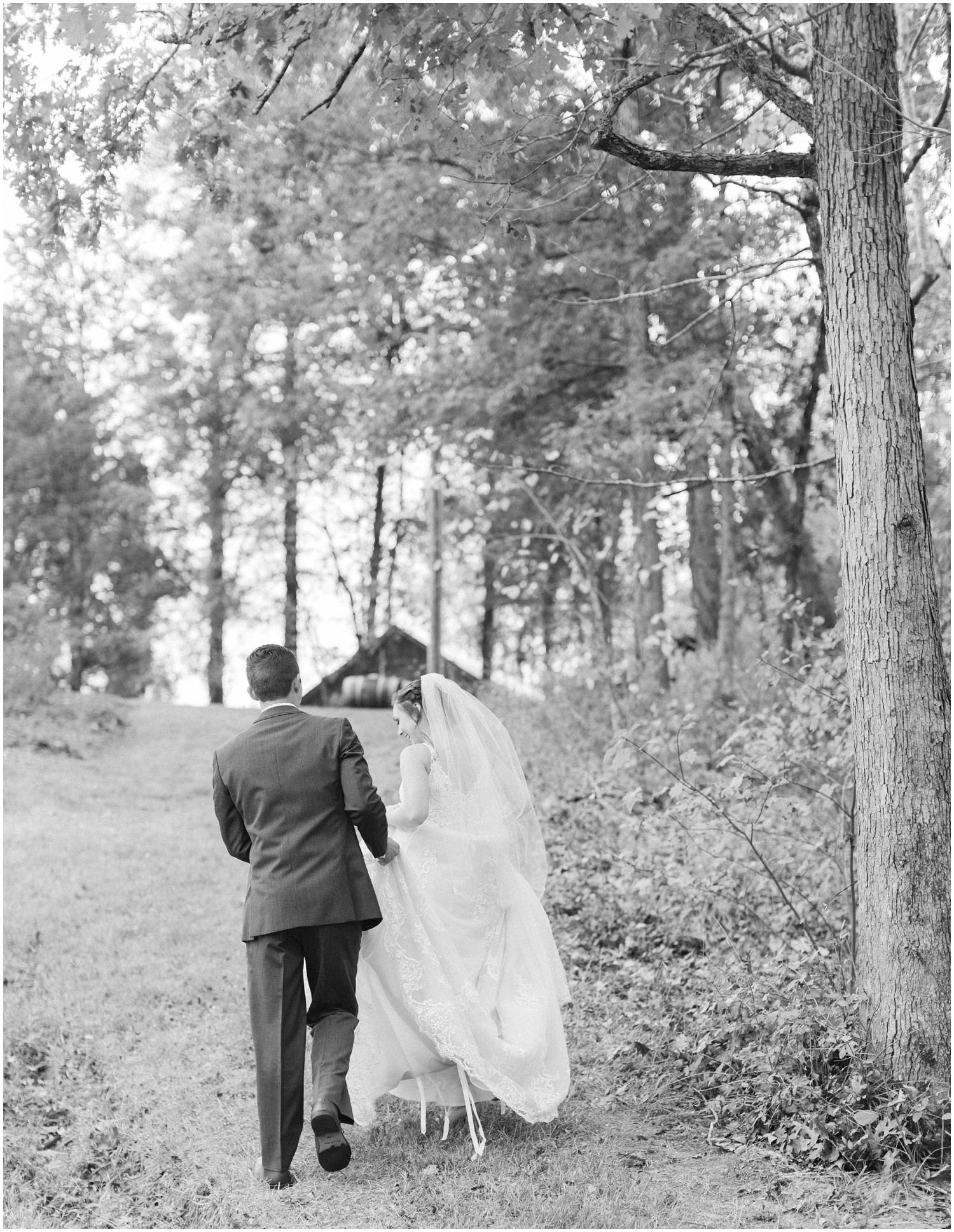 groom helps bride walk up hill during NC wedding photos