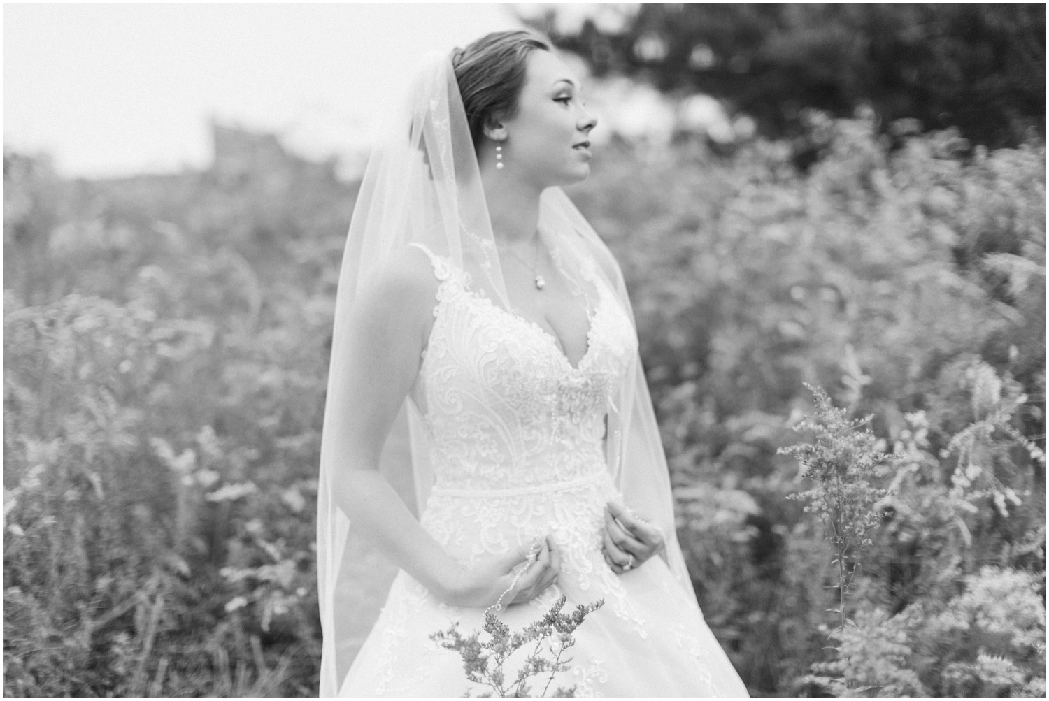 black and white portrait of bride holding veil 
