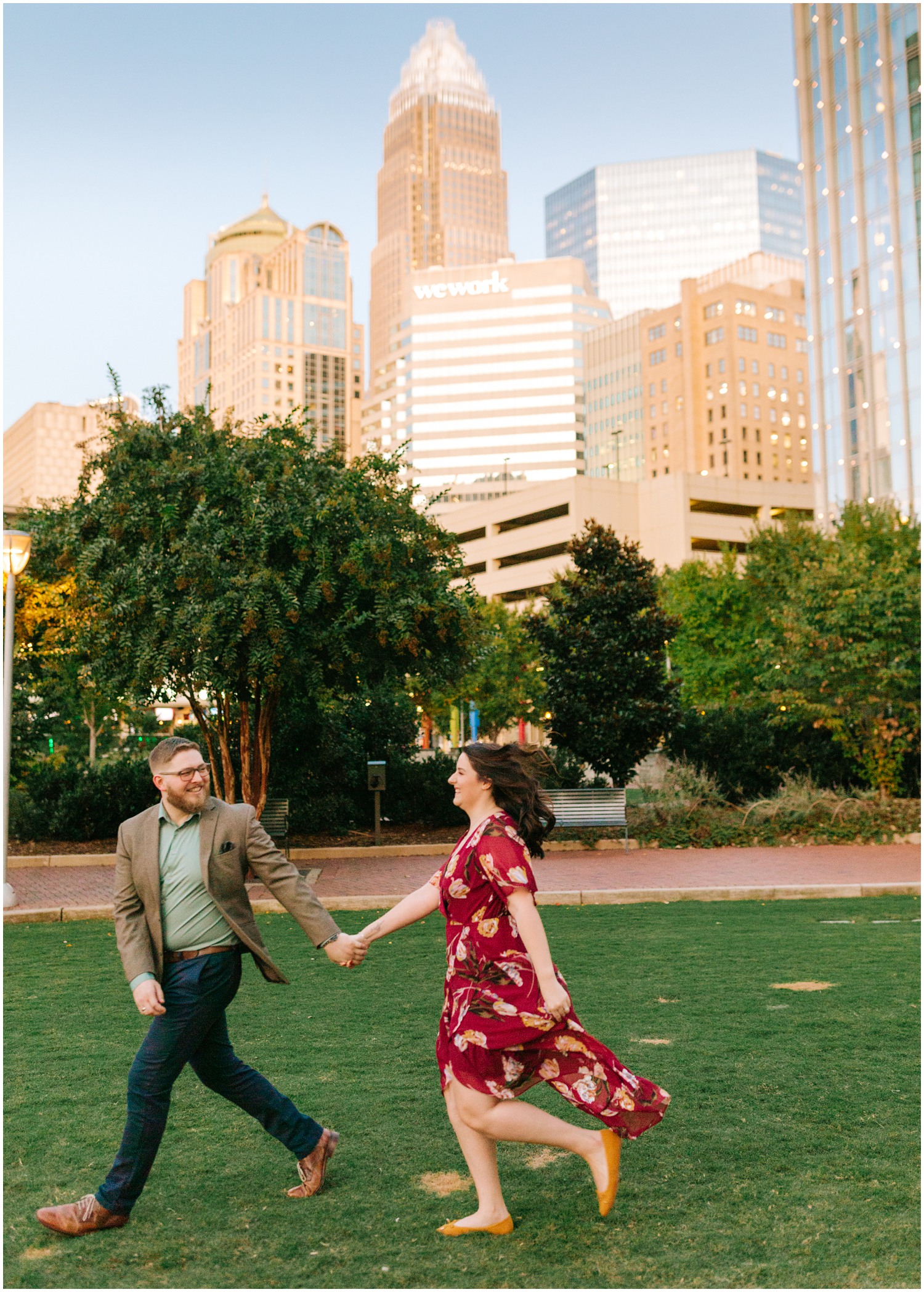 couple runs through Uptown Charlotte park during engagement session