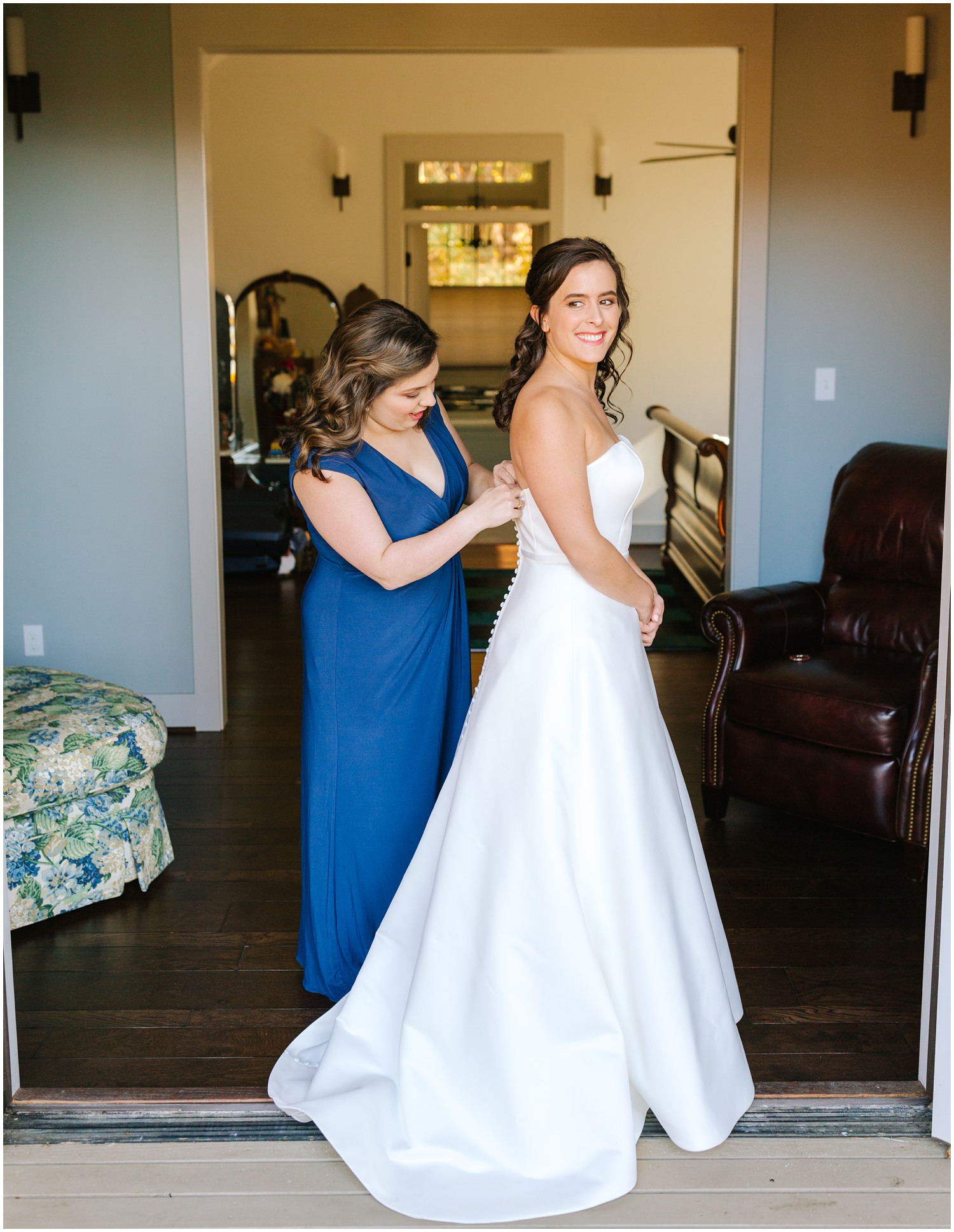 bridesmaid helps button up bride's gown in NC