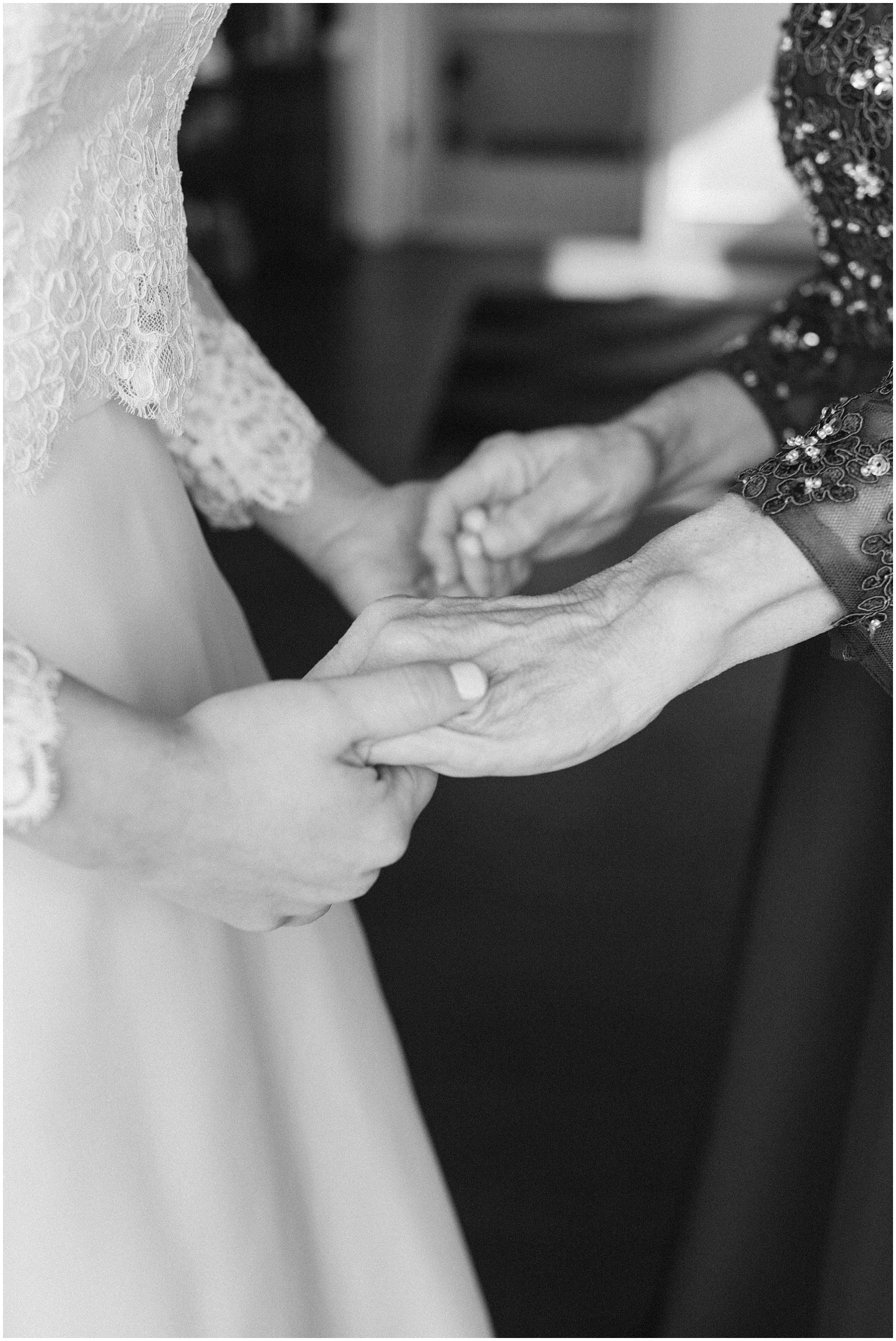 black and white photo of bride holding mom's hand