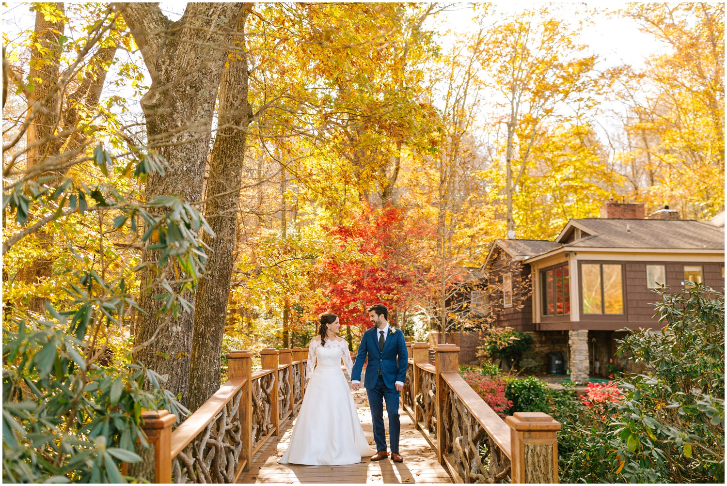 bride and groom smile standing on wooden bridge by cabins at Lake Eden Events