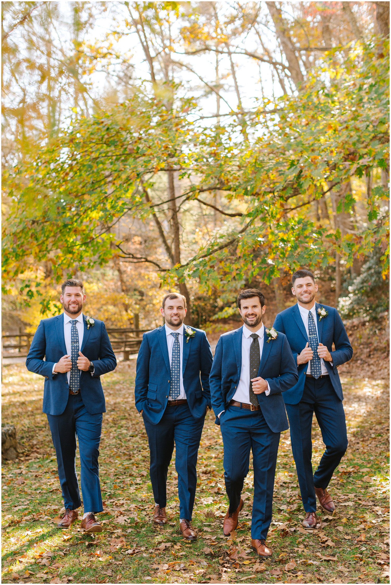 groom and groomsmen in navy suits walk at Lake Eden Events