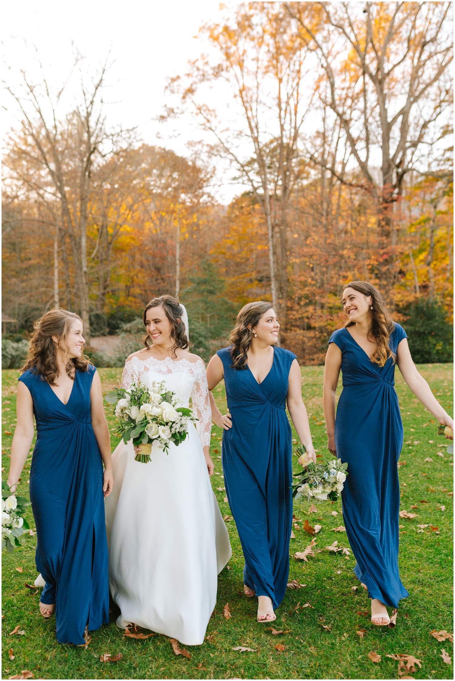 bridesmaids in blue walk by bride with all white bouquets