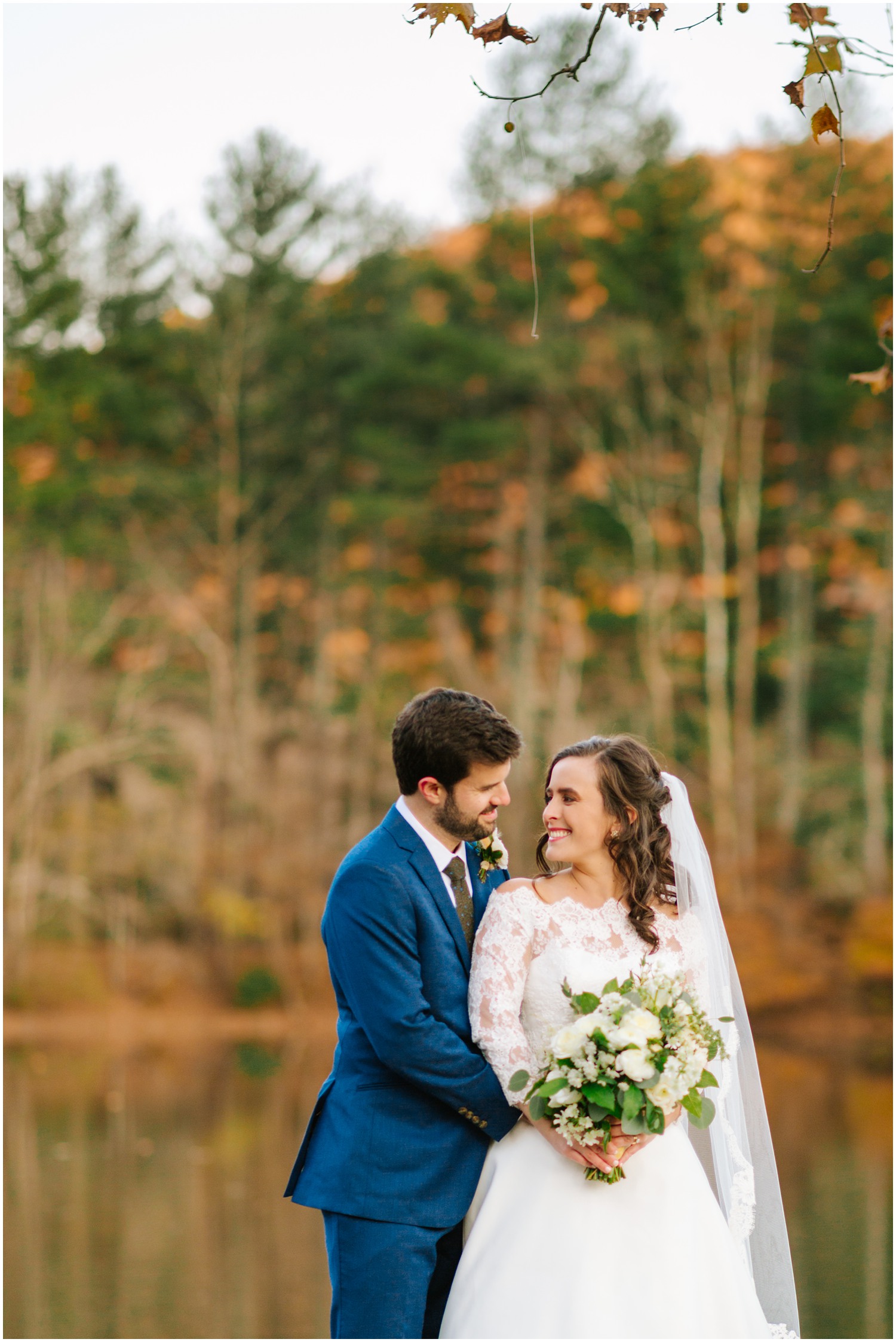 bride and groom smile at each other on dock at Lake Eden
