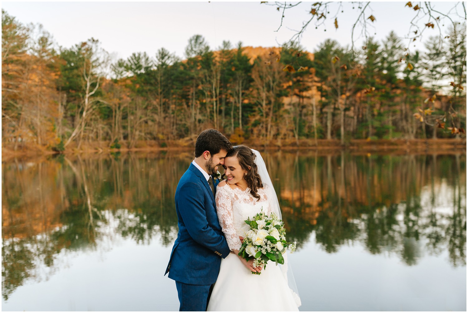 Lake Eden Events with bride holding all white bouquet while wearing veil and groom in navy suit