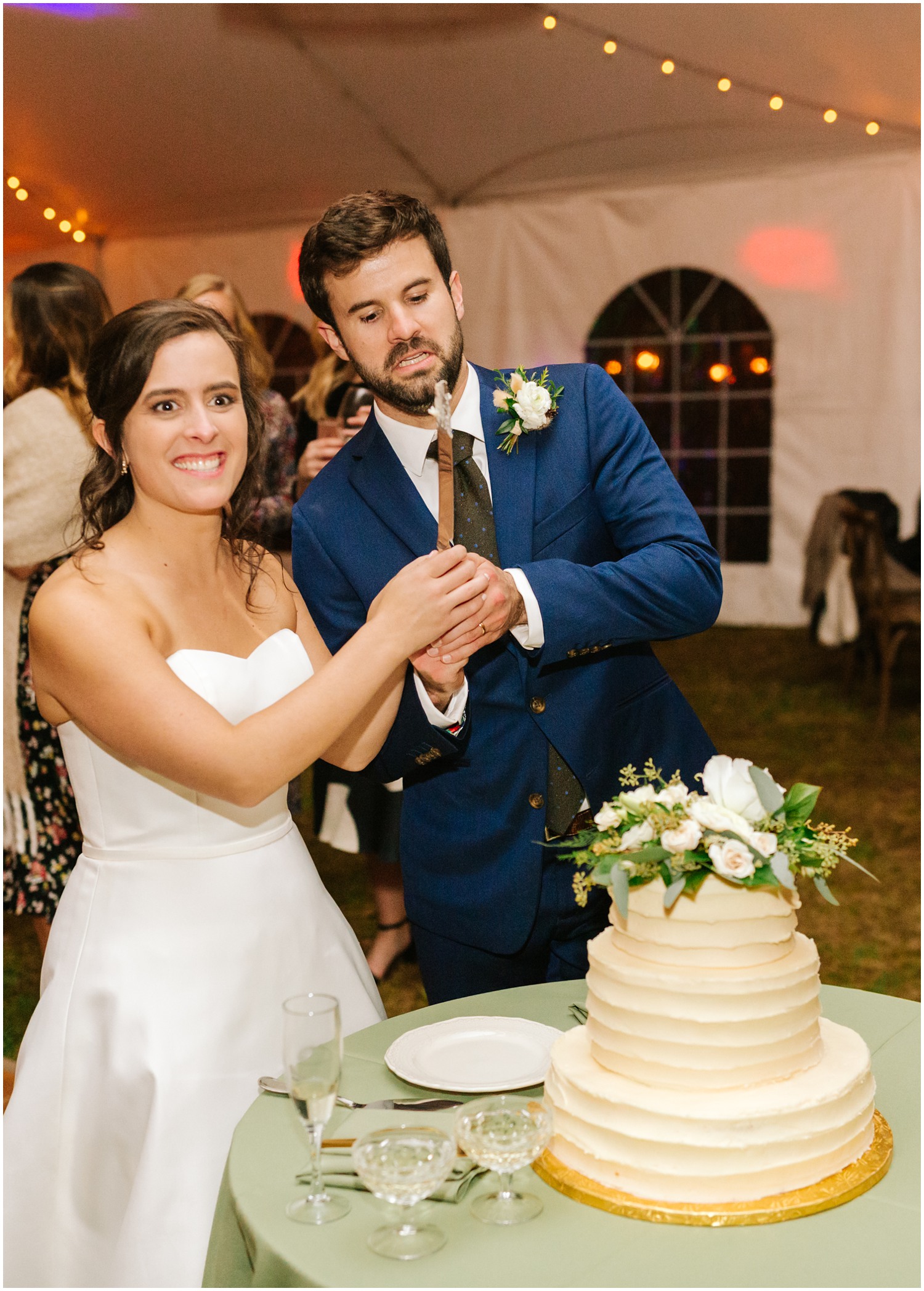 newlyweds take silly photo with cake knife during Asheville wedding reception