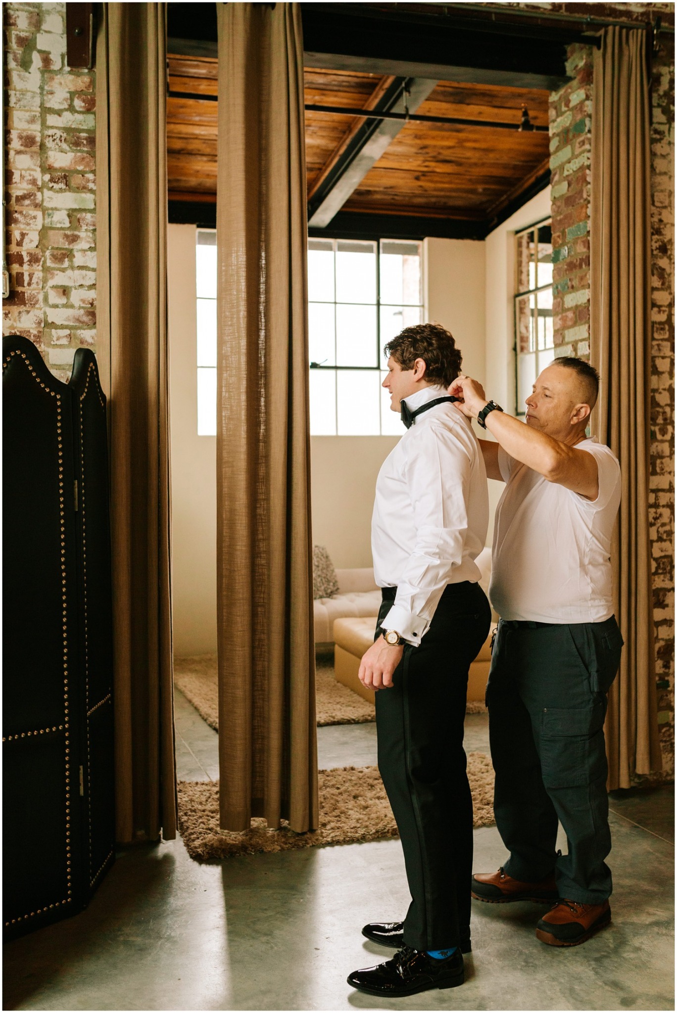 father adjusts son's tie while preparing for wedding day