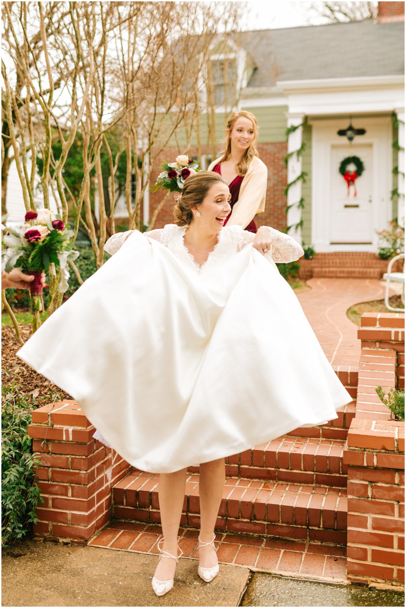 bride shoes off shoes by lifting dress while bridesmaid helps her