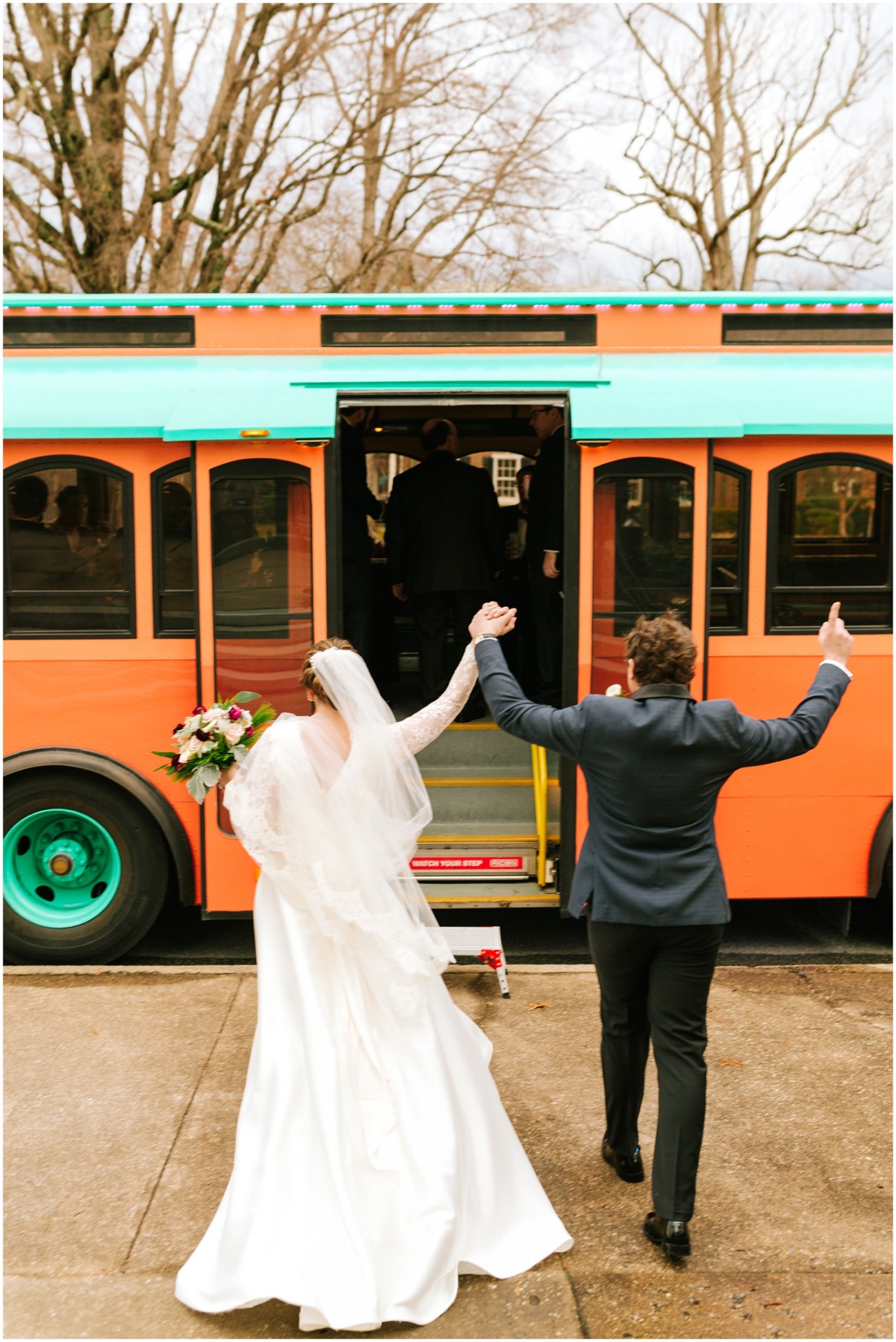 bride and groom cheer while walking onto trolley in NC