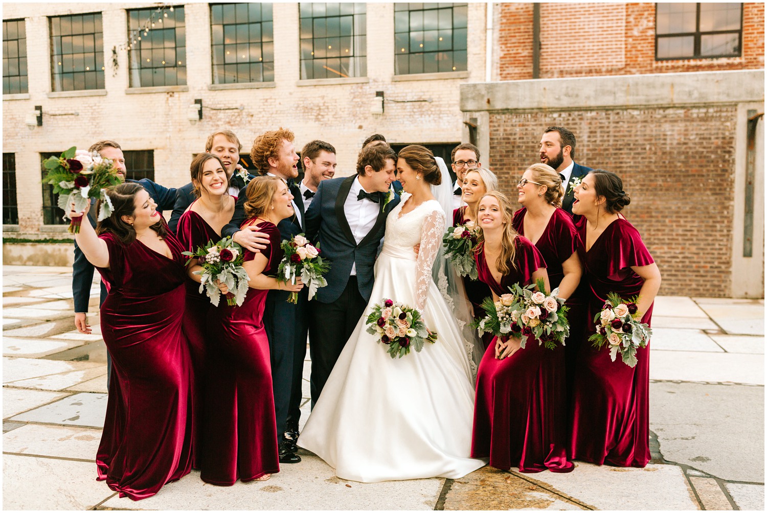 bride and groom nuzzle noses while surrounded by bridal party for winter wedding in NC