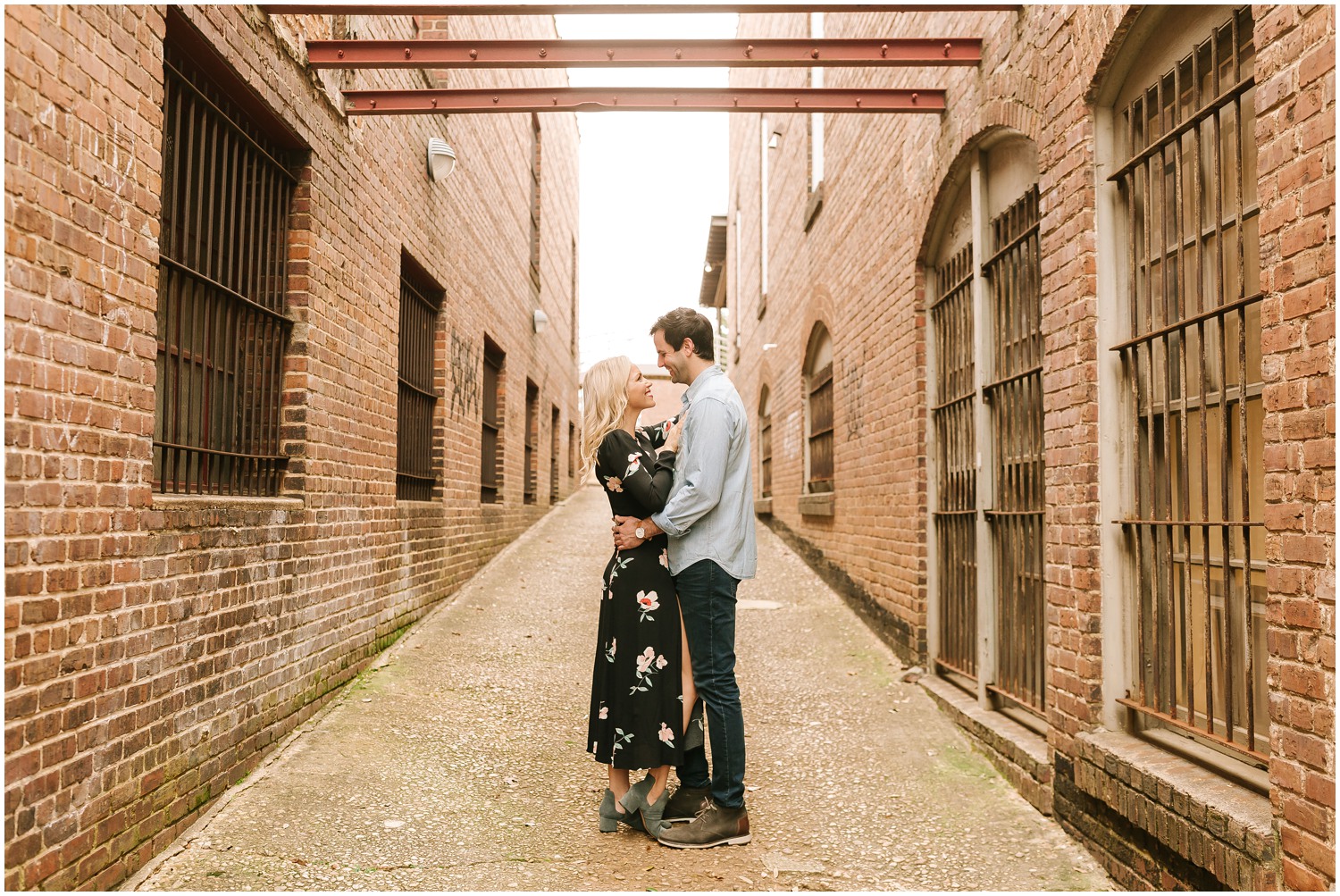 bride and groom stand face to face looking at each other in brick alleyway