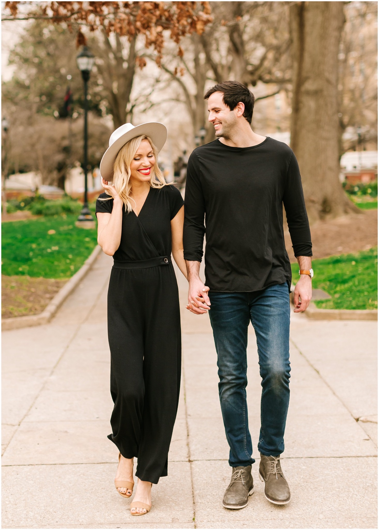 engagement session with bride wearing black jumpsuit and wide brimmed hat and groom in jeans and long sleeve shirt 