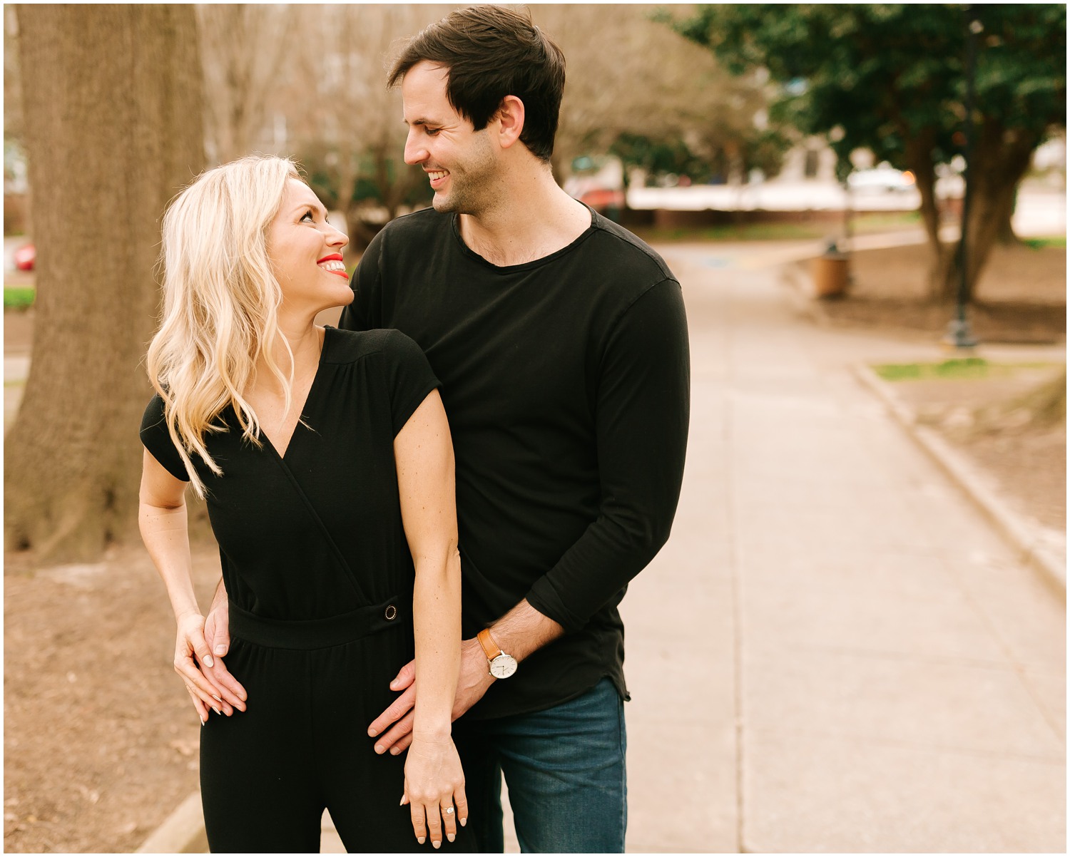 groom holds bride's waist during Downtown Raleigh Engagement Session