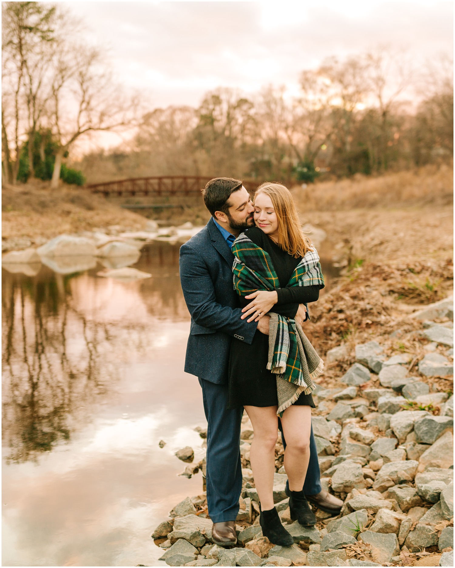 couple poses on rocks by river in Midtown Park in Charlotte NC